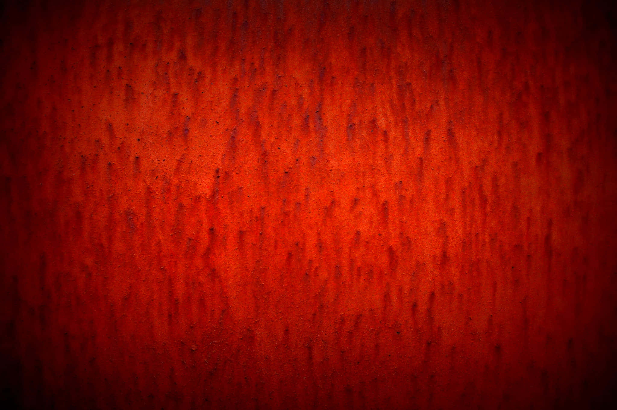 Red Texture 桌布 壁紙 — 質感豐富的深紅色表面，帶有垂直紋理圖案和微妙的深色斑點，逐漸淡出至黑色邊緣。