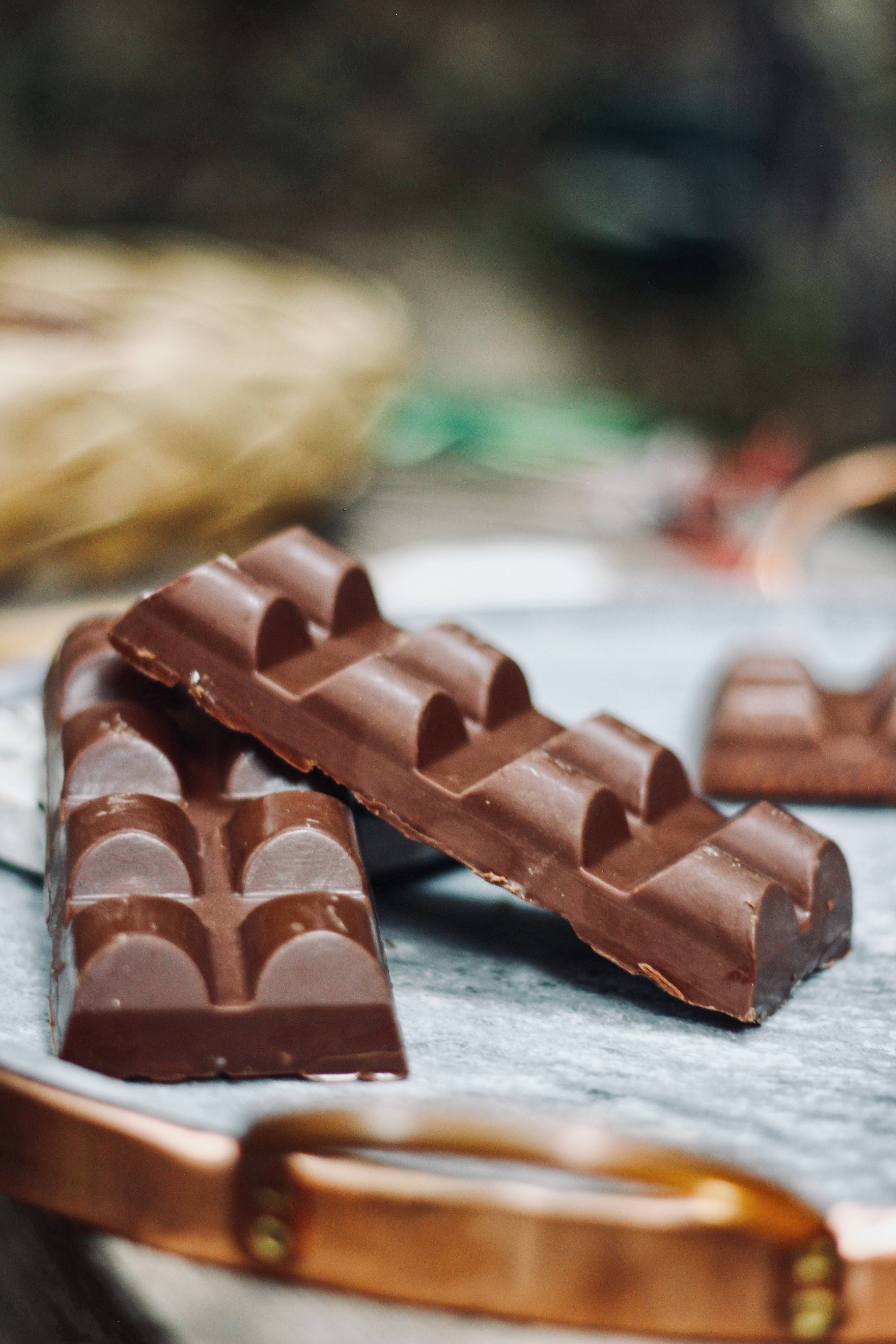 Chocolate 桌布 壁紙 — 質感豐富的黑巧克力條放在涼爽的大理石表面上，旁邊有一個銅托盤。