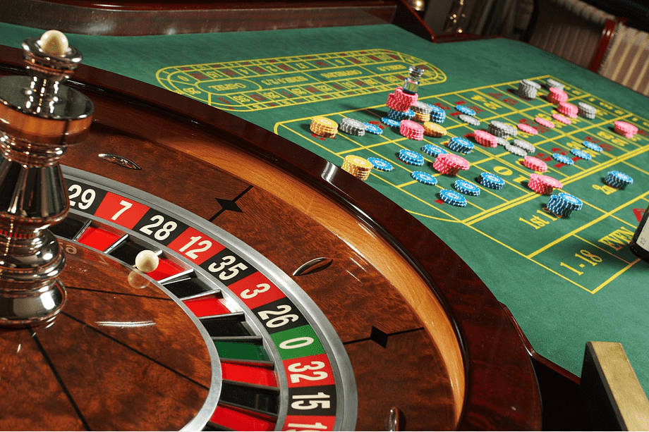 Poker Table 桌布 壁紙 — 賭場輪盤近距離特寫，綠色絨毛投注桌上散落著彩色籌碼。