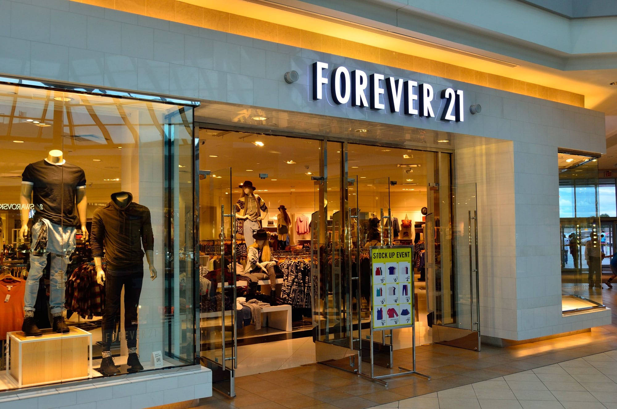 Forever 21 桌布 壁紙 — 購物中心內，一間燈光明亮的Forever 21店舖正面，展示著穿著時尚服裝的人體模型和「Stock Up Event」標誌。