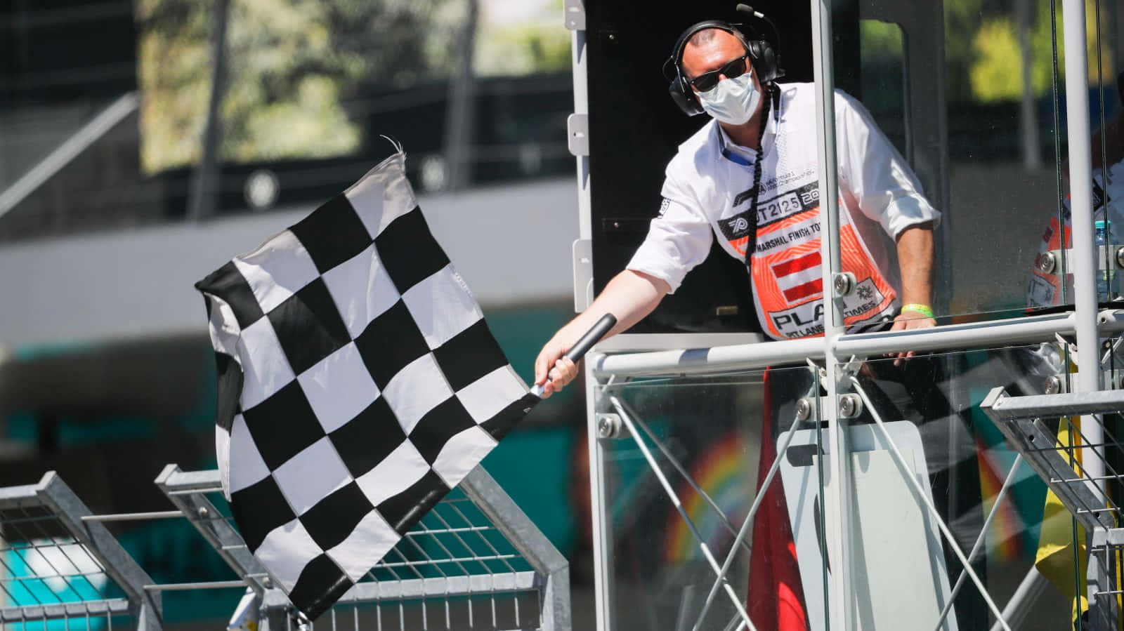 Chequered Flag 桌布 壁紙 — 賽事工作人員在晴朗的賽車活動中從塔樓揮動方格旗。