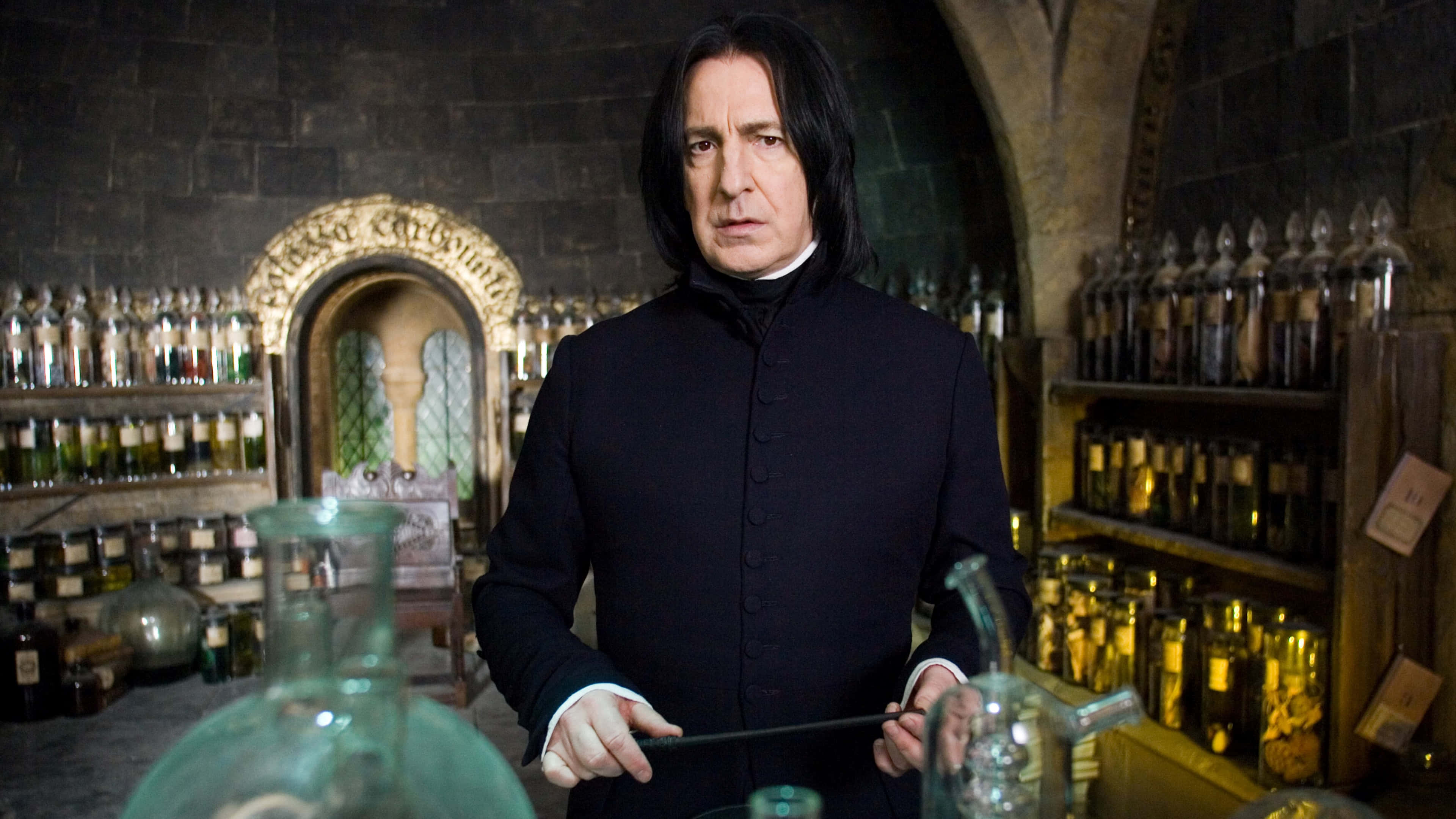 Harry Potter 4K 桌布 壁紙 — 賽佛勒斯·石內卜站在光線昏暗的魔藥學教室，周圍的架子上擺滿了裝有發光液體的玻璃瓶。