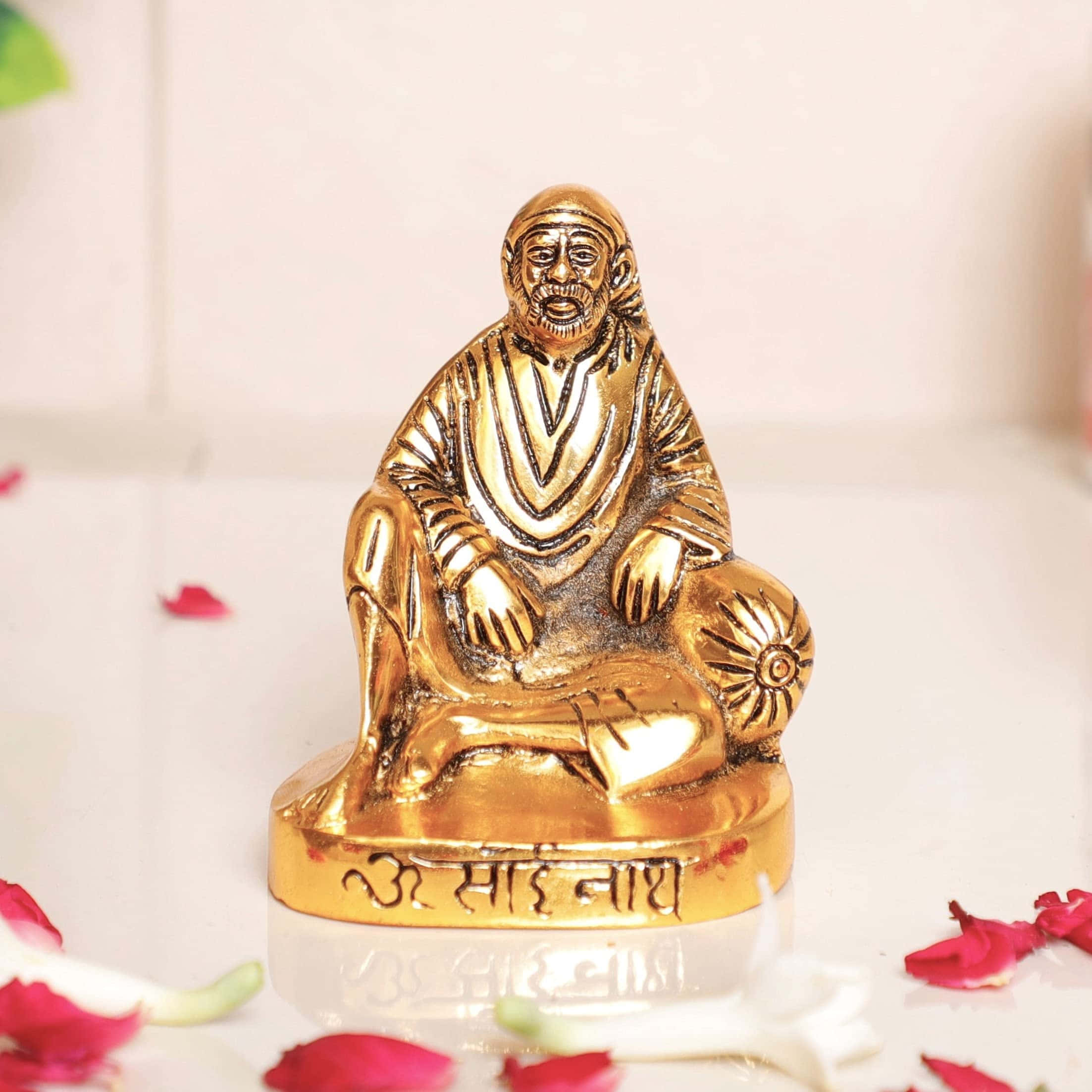figure 桌布 壁紙 — 賽巴巴的金色雕像，坐著冥想，周圍散落著紅玫瑰花瓣在反光表面上。