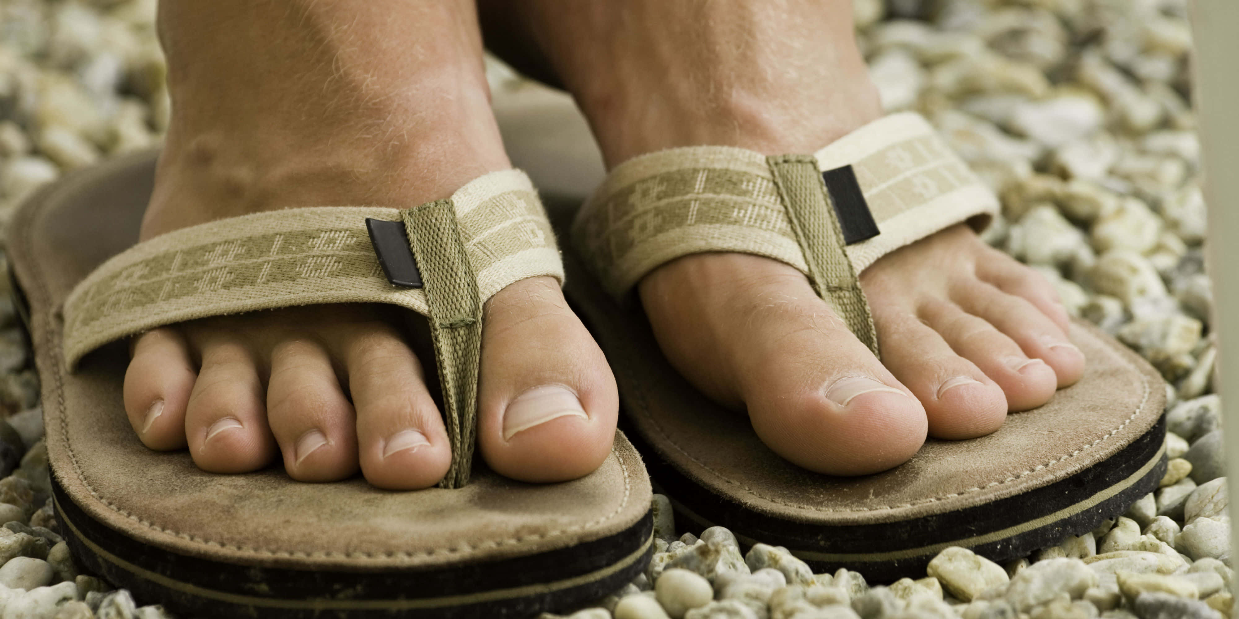feet 桌布 壁紙 — 赤腳穿著米色人字拖涼鞋，擱在細小灰色卵石上的特寫。