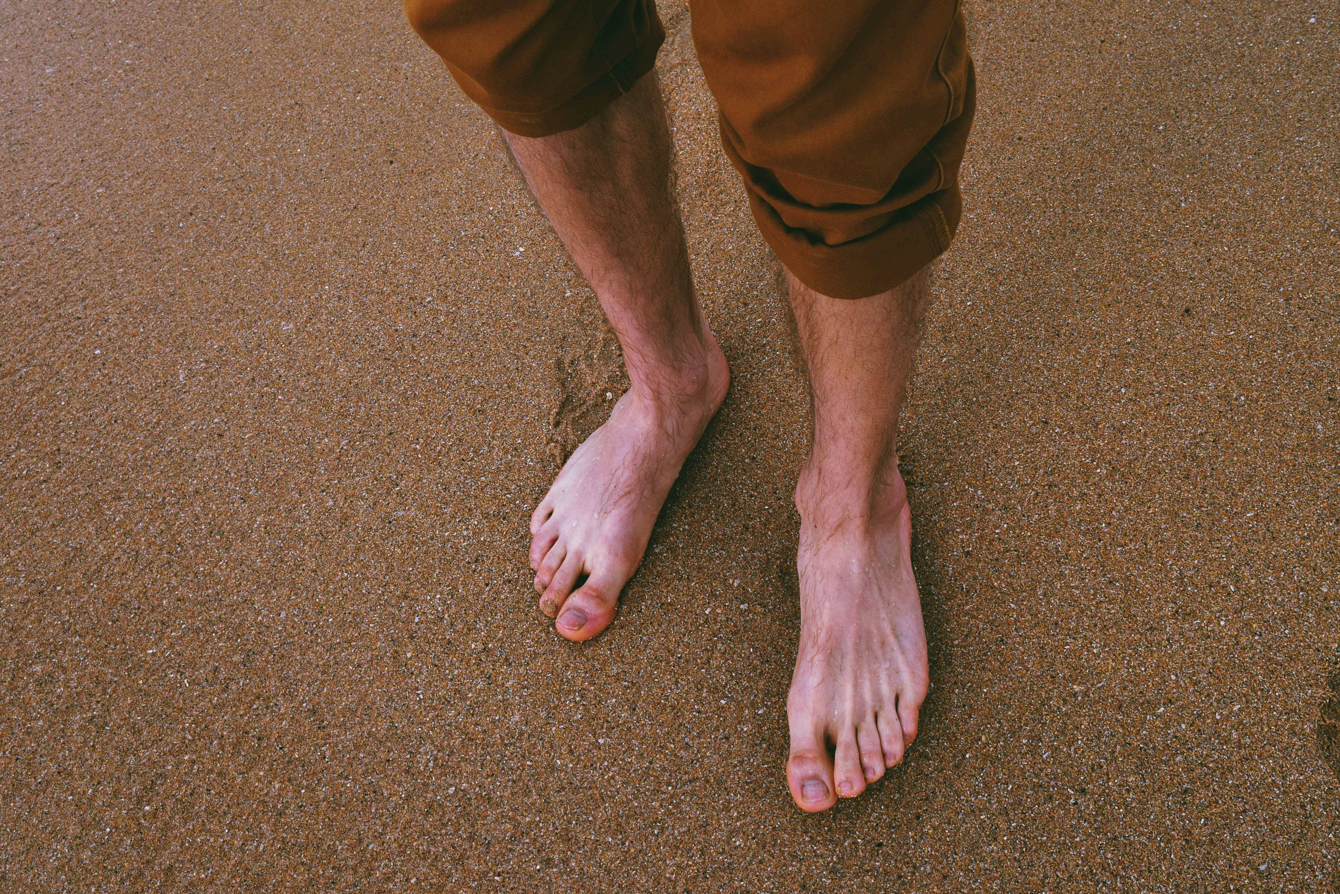 feet 桌布 壁紙 — 赤腳站在溫暖的金色沙灘上，上方可見棕色捲起的褲子。
