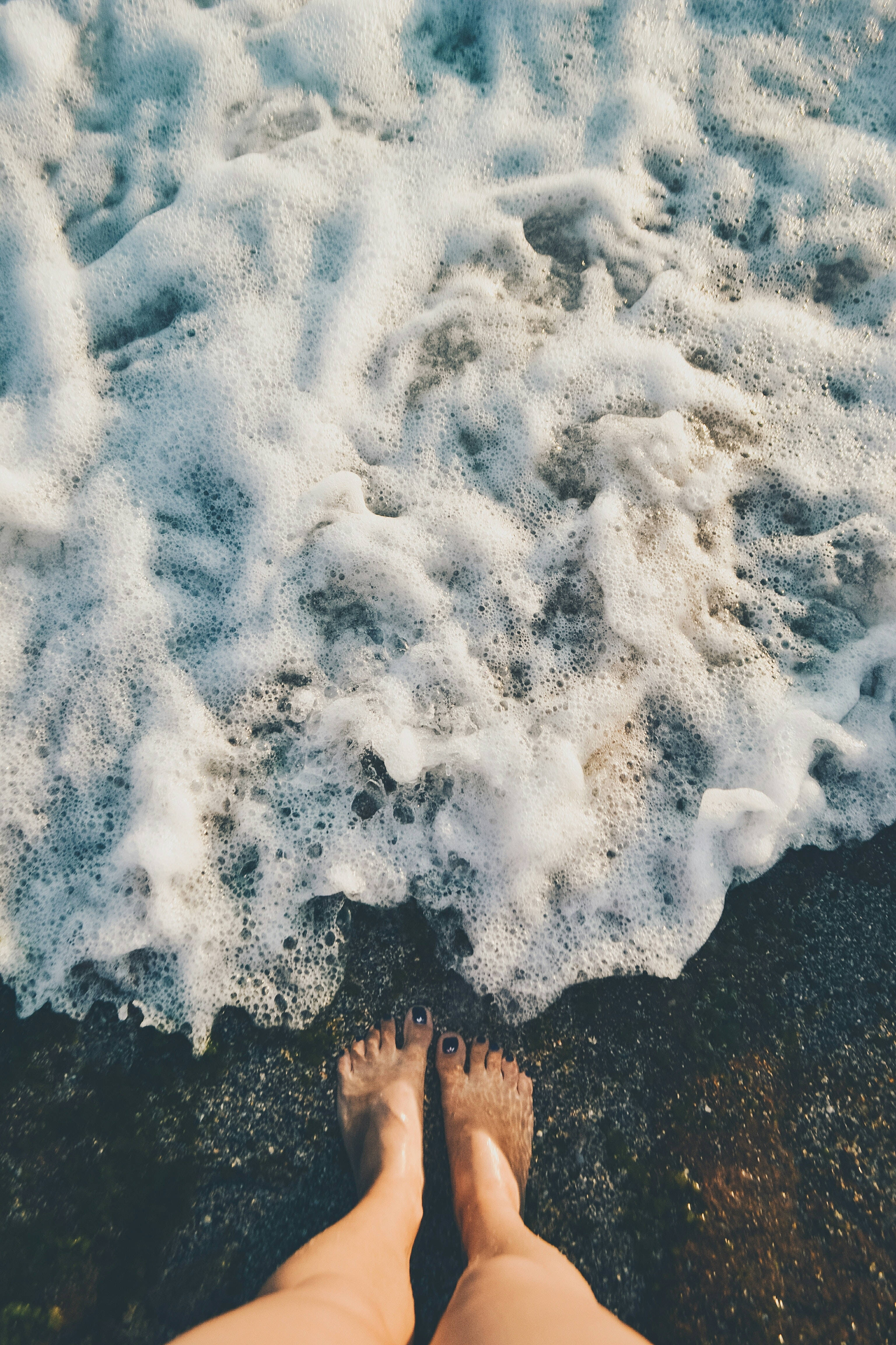 waves 桌布 壁紙 — 赤腳站在陽光明媚的海灘上，泡沫般的海浪邊緣。