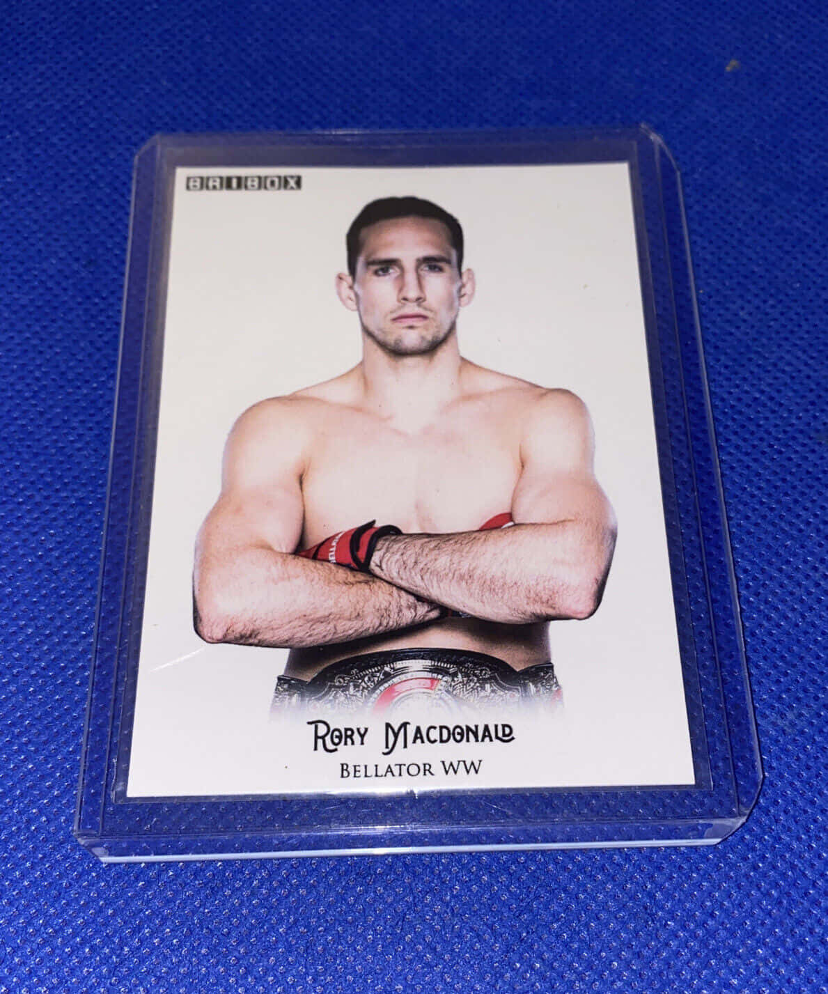 MMA 桌布 壁紙 — 赤裸上身的 Rory MacDonald 交叉雙臂，在藍色紋理背景上佩戴冠軍腰帶。