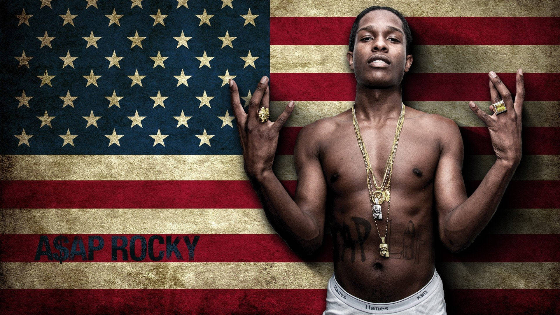 rocky 桌布 壁紙 — 赤裸上身的ASAP Rocky自信地擺姿勢，背景是破舊的美國國旗，飾有金鍊和戒指。