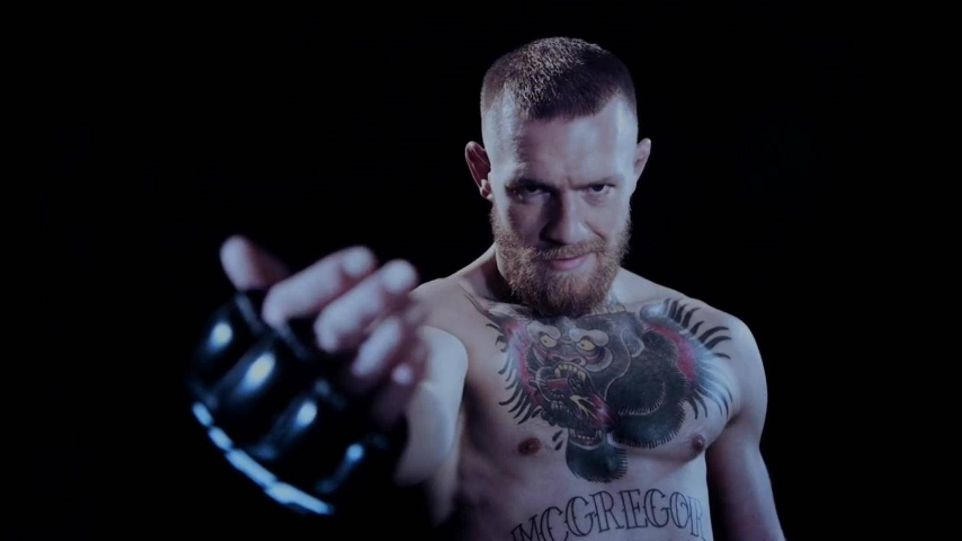 Mcgregor 桌布 壁紙 — 赤裸上身的康納·麥格雷戈，眼神兇猛，胸口有刺青，在黑色背景前伸出戴手套的拳頭。