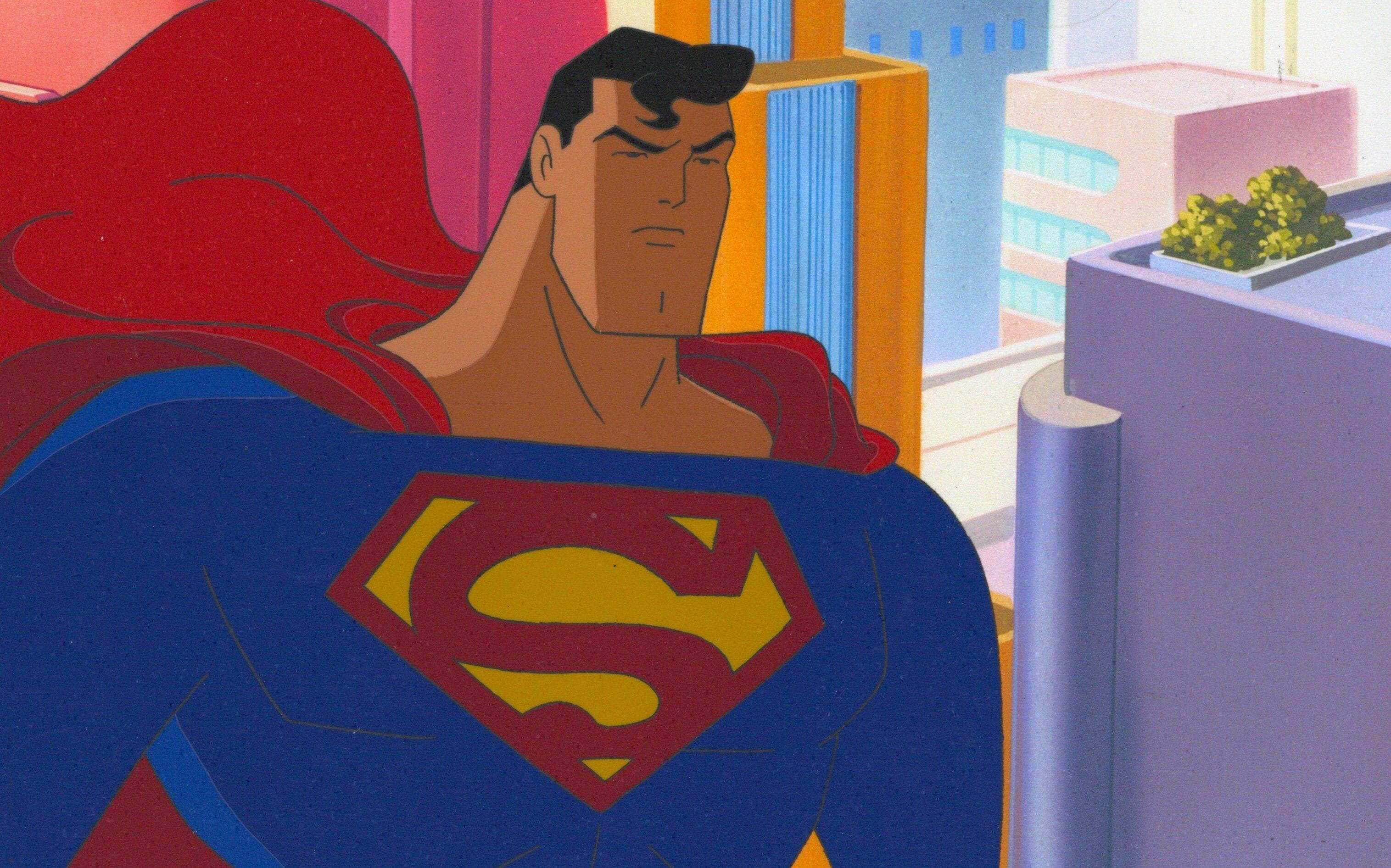 Superman The Animated Series 桌布 壁紙 — 超人穿著標誌性的藍色服裝、紅色斗篷和黃色「S」盾牌，在風格化的城市背景下高高站立。