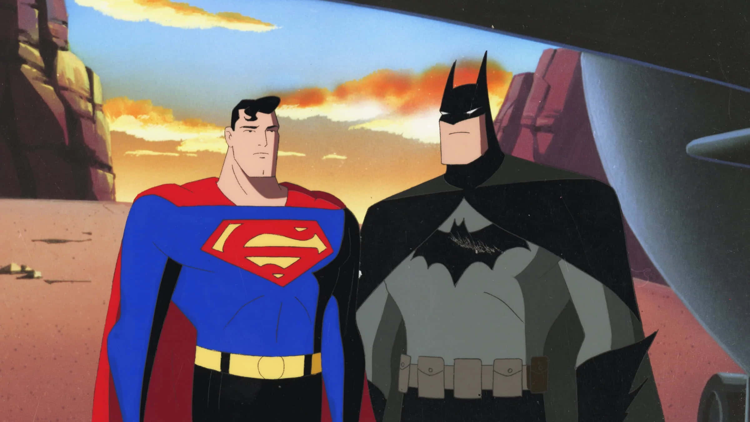 Superman The Animated Series 桌布 壁紙 — 超人與蝙蝠俠在沙漠峽谷中並肩而立，夕陽西下，身後是溫暖的橙色雲彩。