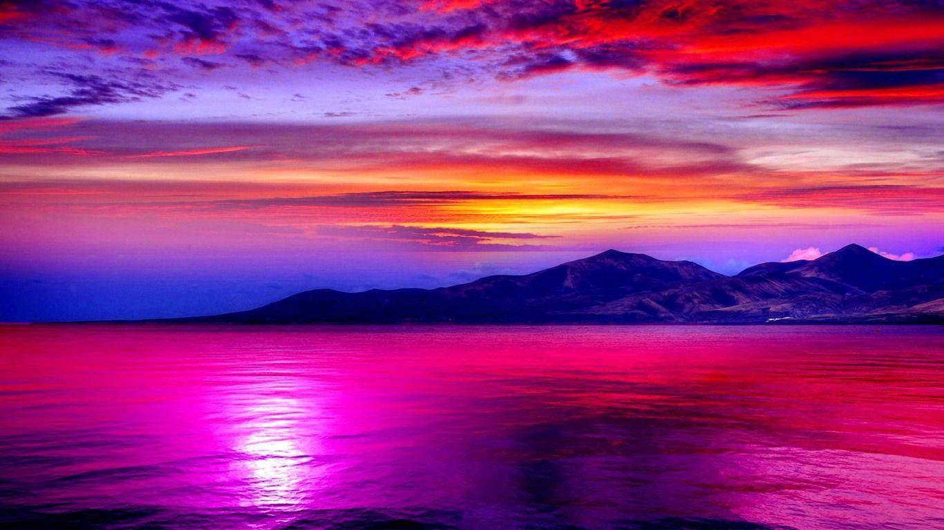 風景動畫 桌布 壁紙 — 超現實的夕陽在遠山之上，以鮮豔的洋紅色和深紅色渲染天空和水面。