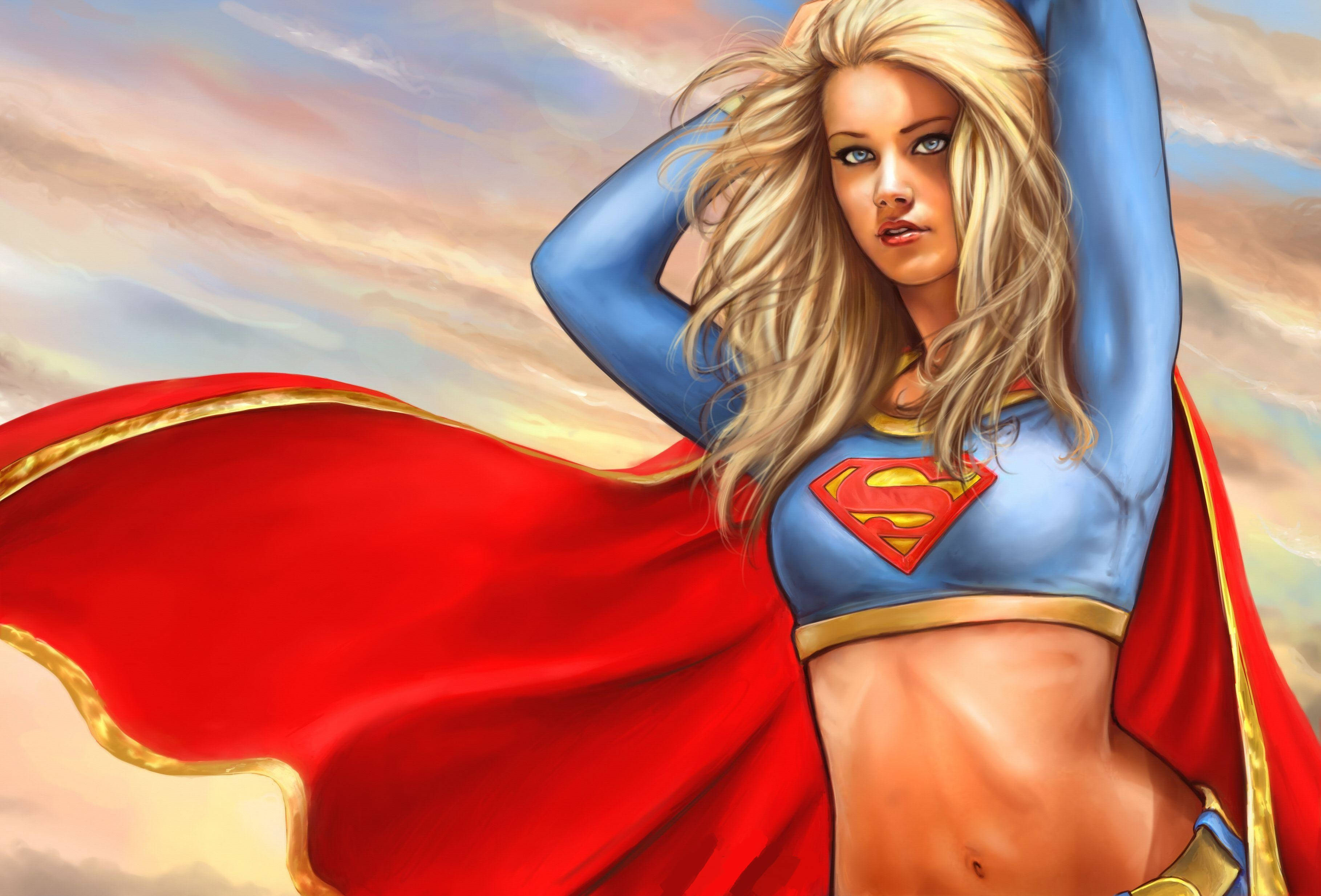Superwoman 桌布 壁紙 — 超級女人自信地站在柔和天空下，紅色斗篷在她周圍戲劇性地飄揚。