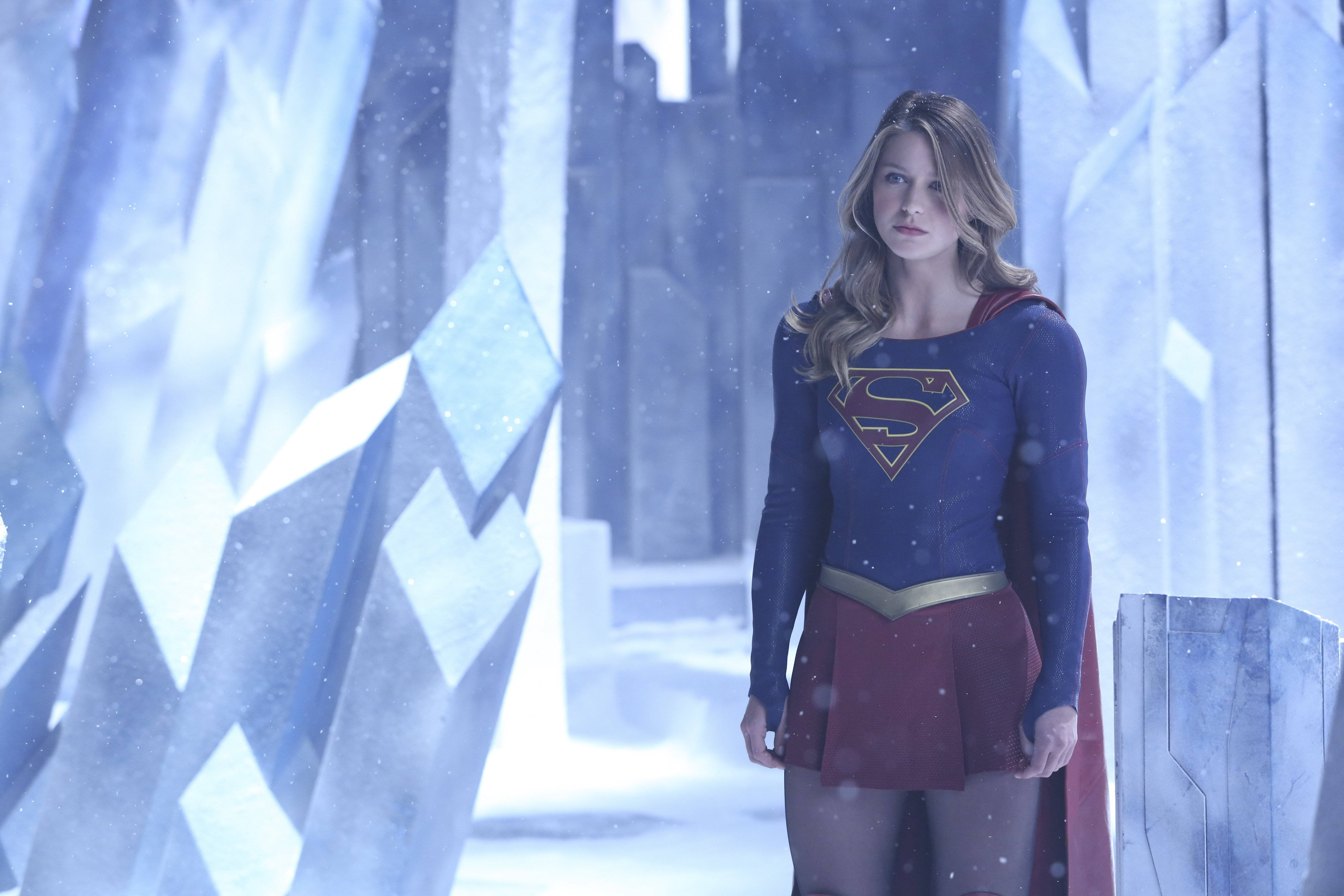 Melissa Benoist 桌布 壁紙 — 超級女孩在一個冰冷的結晶室中擺好姿勢，雪花在她標誌性的藍色和紅色服裝周圍飄舞。