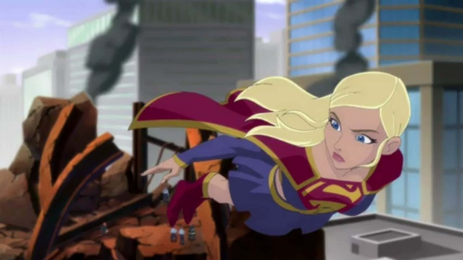 Superman Unbound 桌布 壁紙 — 超級女孩飛過城市景觀，身後受損的建築物冒出濃煙。