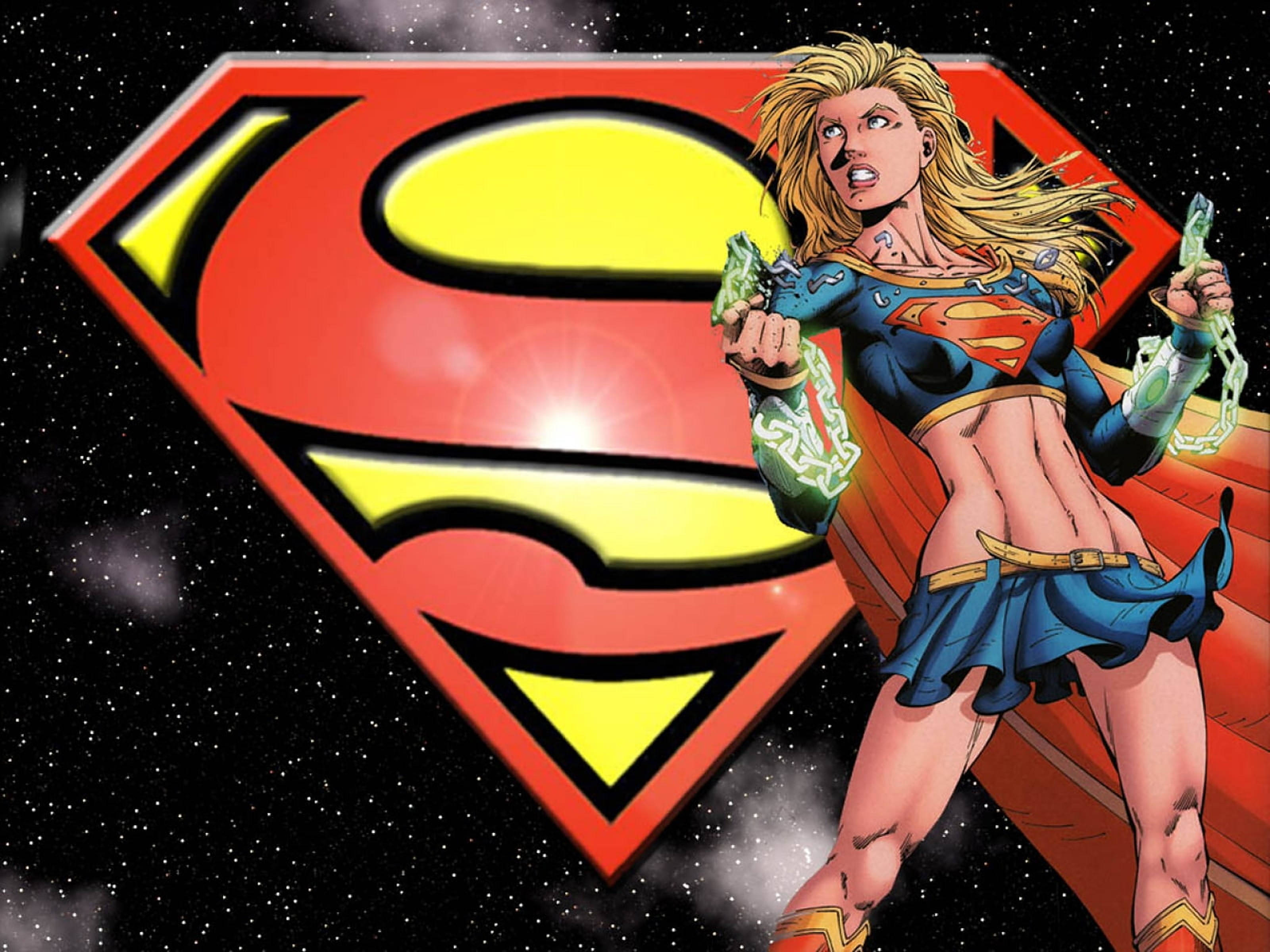 Superwoman 桌布 壁紙 — 超級女超人動態地站在太空中，面前是一個發光的紅黃色S盾牌，揮舞著綠色能量鏈。