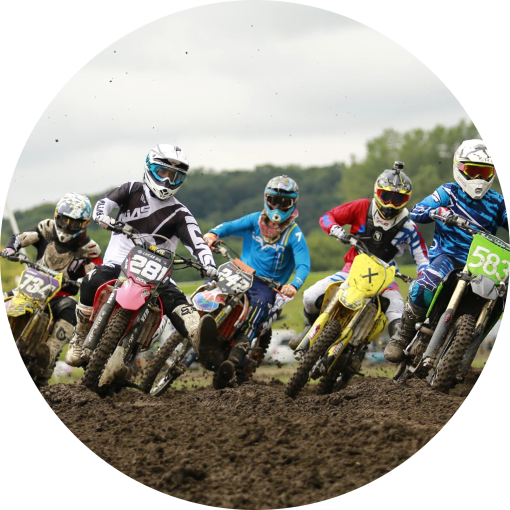Motocross 桌布 壁紙 — 越野摩托車手在多雲的天空下，在泥濘的地形上激烈競賽，泥土飛揚。