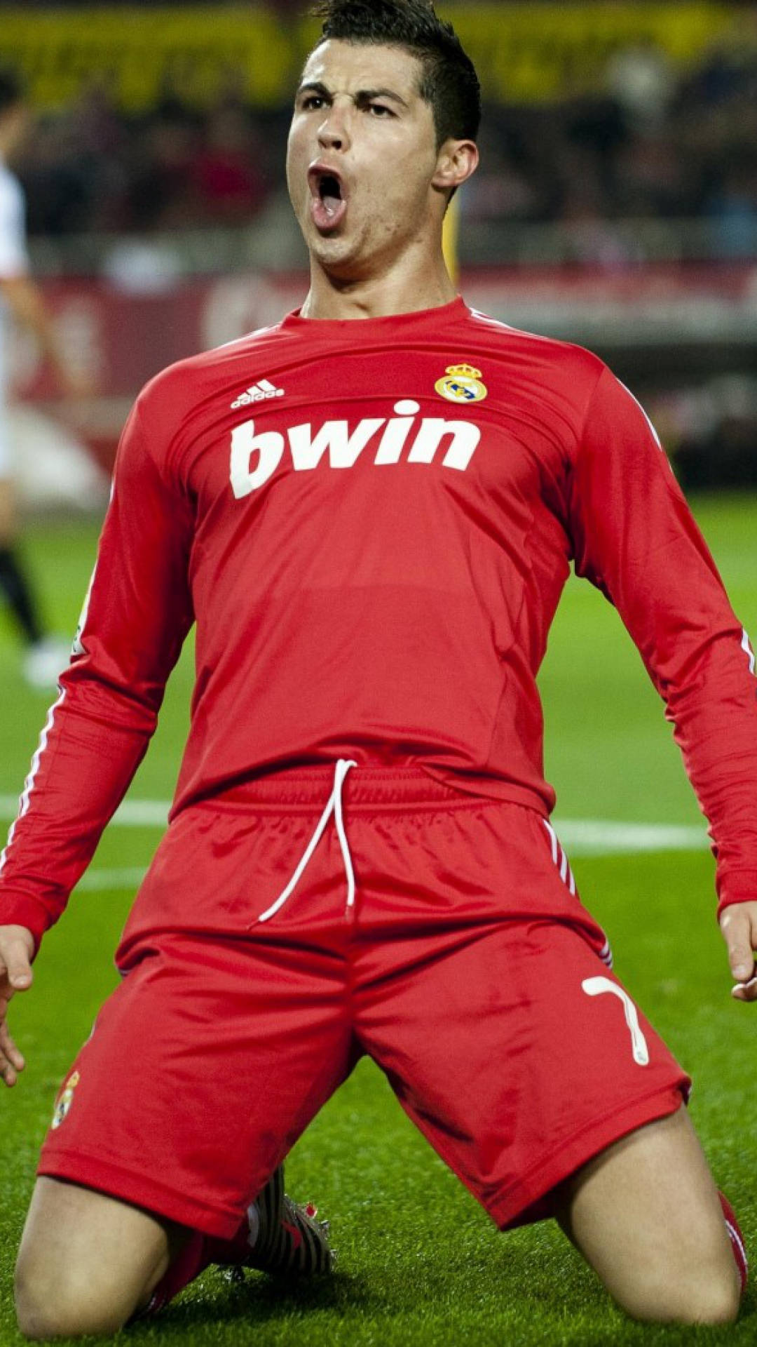 Ronaldo 桌布 壁紙 — 足球員克里斯蒂亞諾·羅納度在草地上跪著，身穿紅色球衣，比賽中張開嘴巴發出勝利的呼喊。