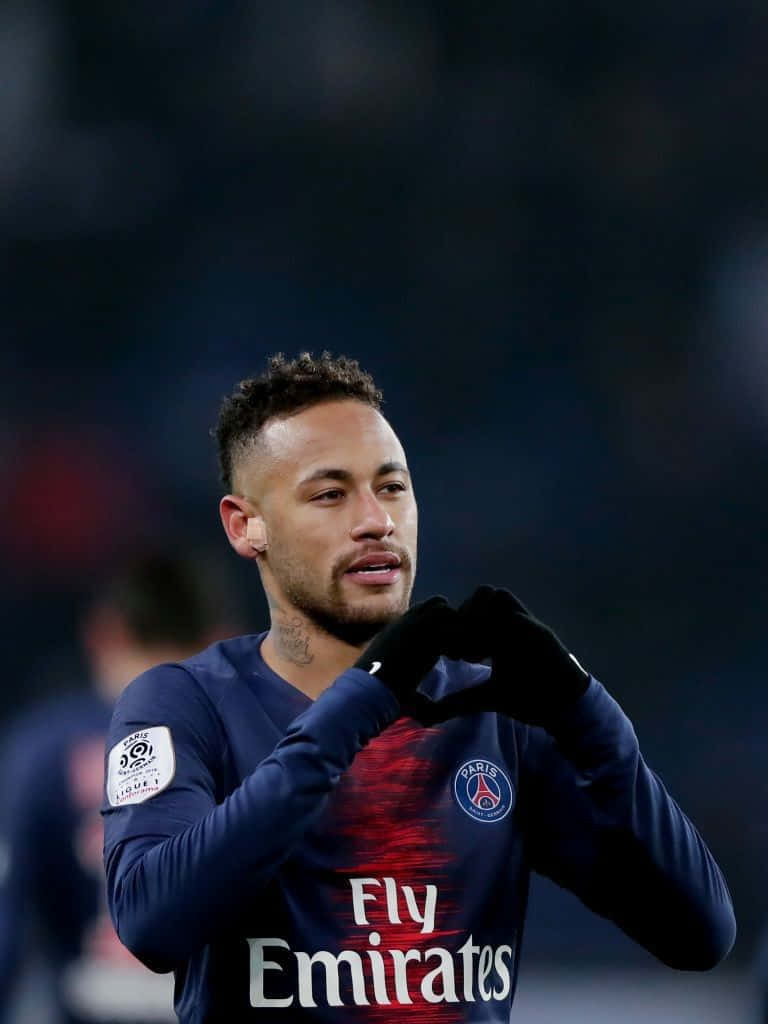 内马尔 桌布 壁紙 — 足球員內馬爾（Neymar Jr）戴著手套，雙手比心，身穿巴黎聖日耳曼球衣，在球場燈光下。