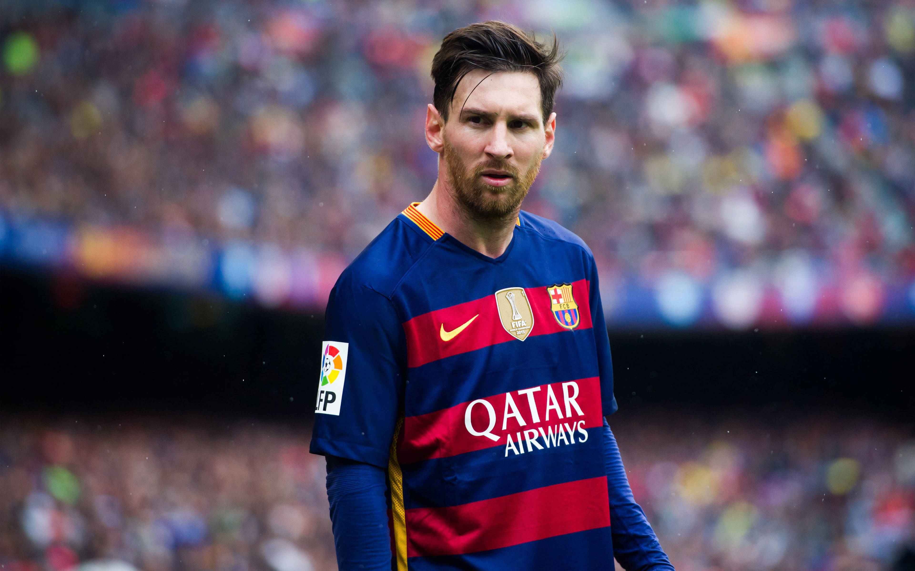 Messi 4K Ultra HD 桌布 壁紙 — 足球員梅西身穿藍紅條紋球衣，專注地站在擠滿觀眾的球場上。