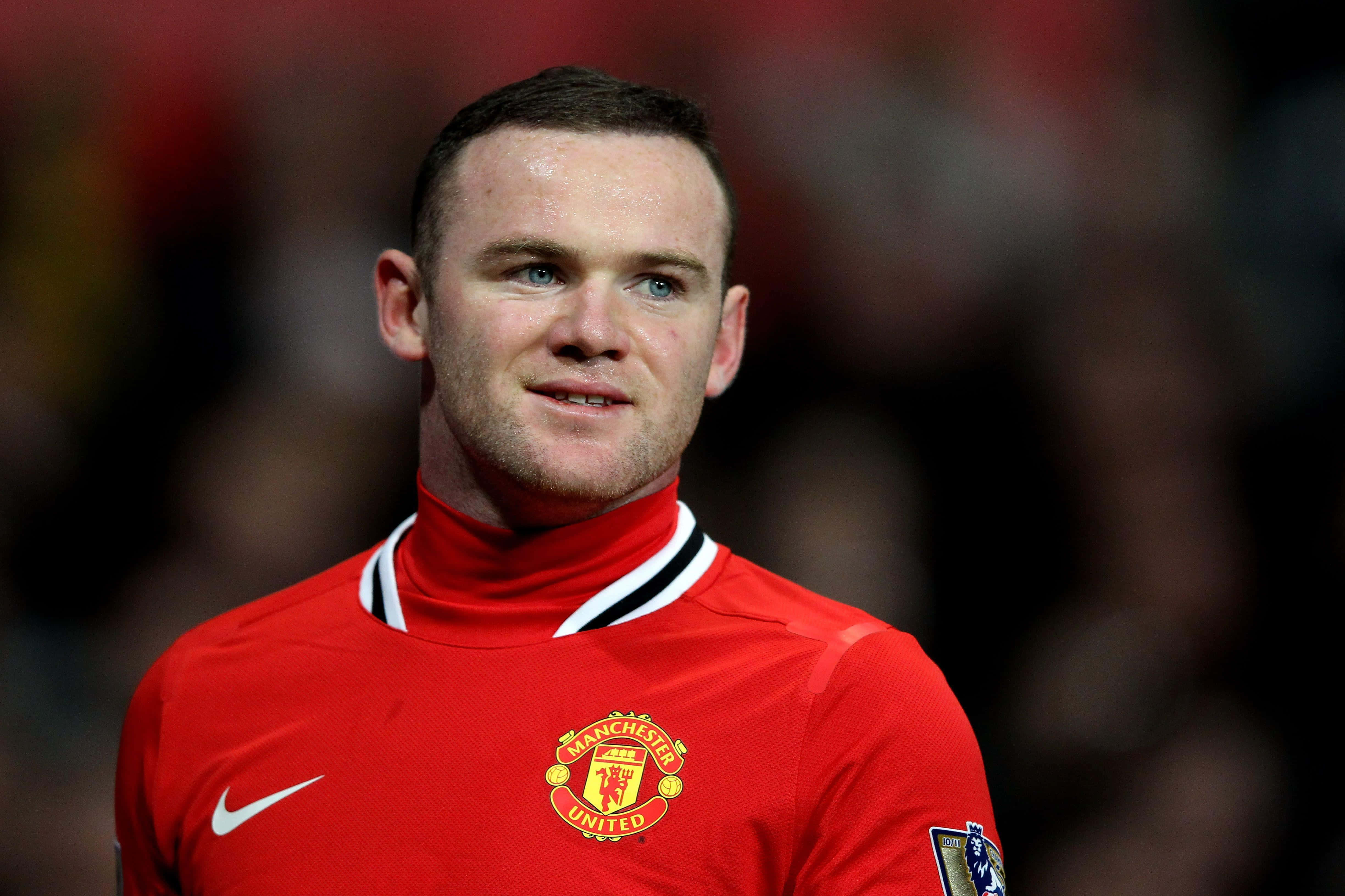 Wayne Rooney 桌布 壁紙 — 足球員韋恩·魯尼身穿紅色曼聯球衣的特寫，背景是模糊的球場人群。