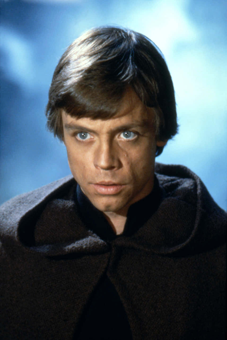 Return Of The Jedi 桌布 壁紙 — 路克·天行者身穿深色長袍，以柔和藍色雲朵背景的特寫肖像。
