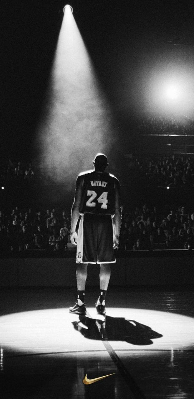 Kobe Bryant iPhone 桌布 壁紙 — 身穿24號球衣的籃球運動員獨自站在球場的聚光燈下，背景有群眾。