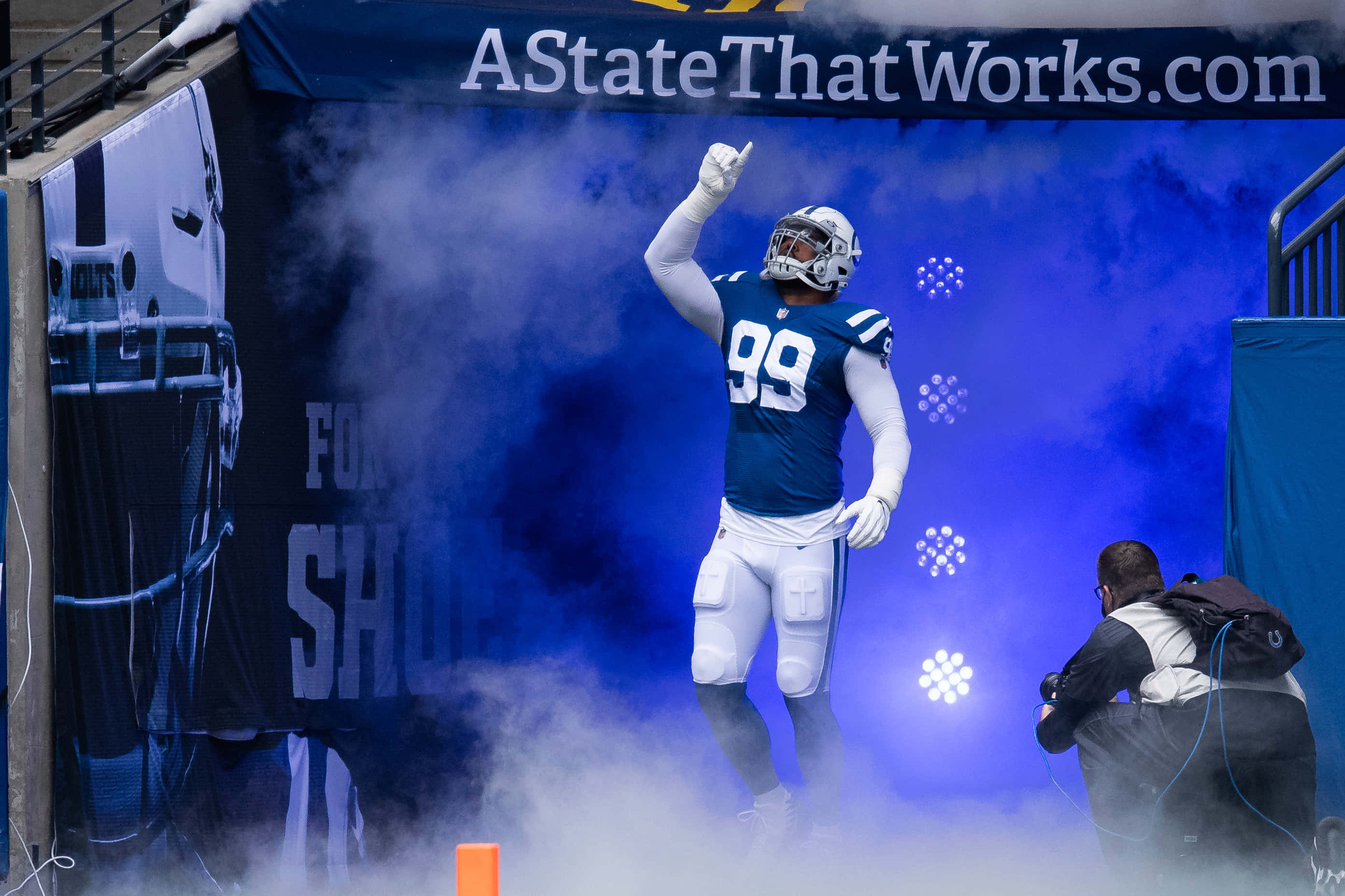 Football Players 桌布 壁紙 — 身穿99號球衣的足球員從藍色煙霧中出現在球場上，攝影師捕捉了這一刻。