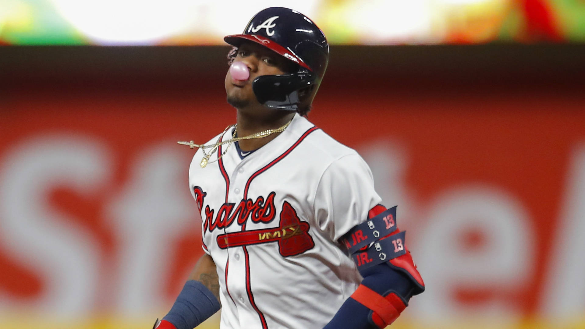 Acuna 桌布 壁紙 — 身穿亞特蘭大勇士隊球衣的棒球選手在夜間比賽中戴著頭盔和金項鍊吹泡泡糖。
