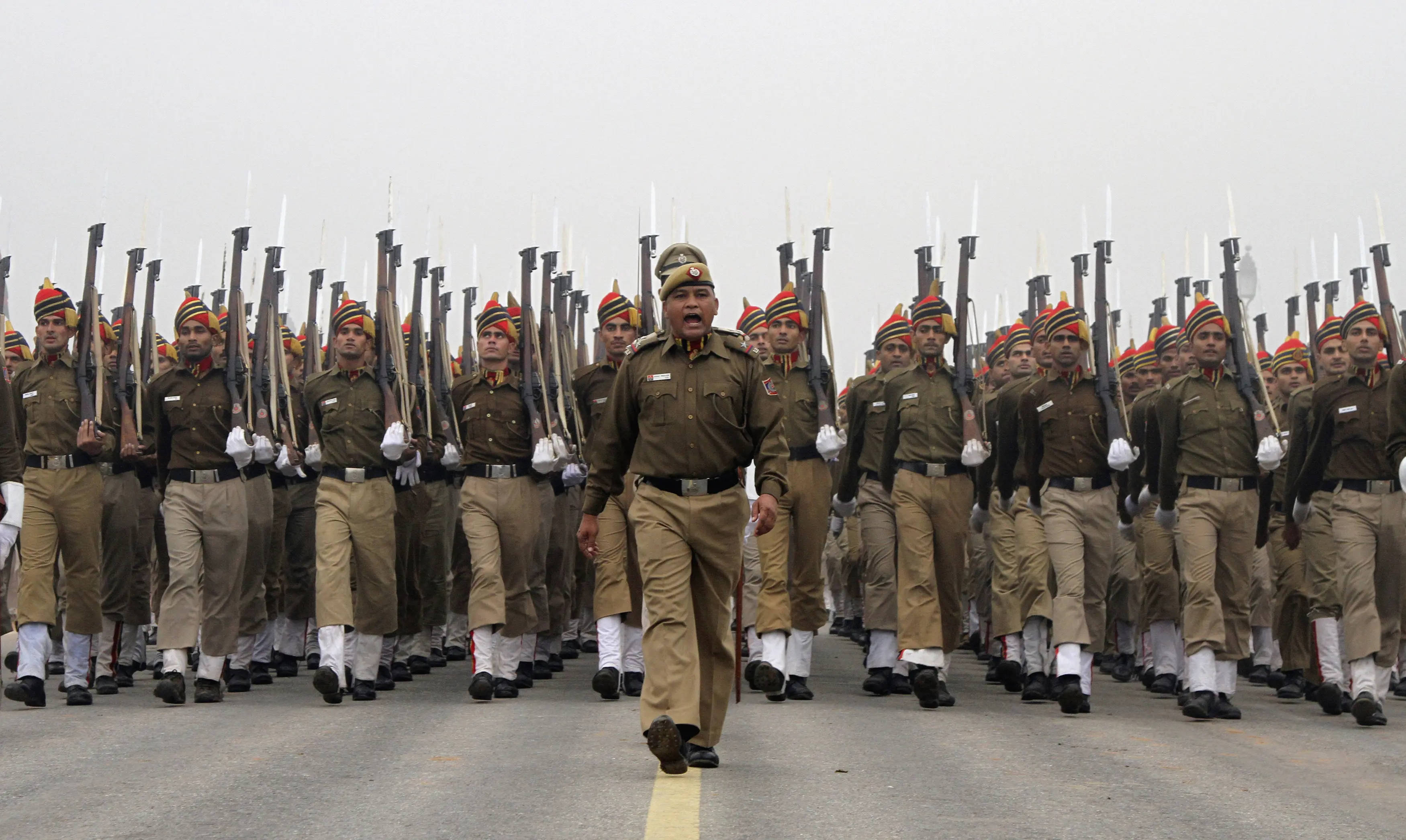 Indian 桌布 壁紙 — 身穿制服的士兵在陰天之下，沿著鋪砌的道路以精確的隊形行進，步槍直立握持。