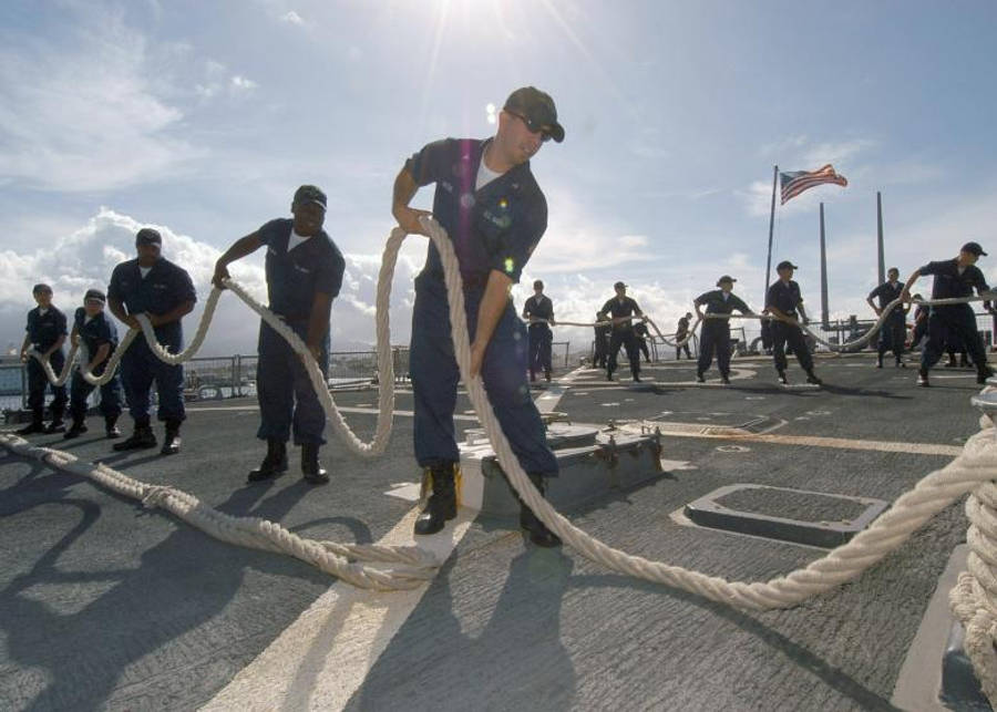 Teamwork 桌布 壁紙 — 身穿制服的海軍士兵在陽光明媚的甲板上用力拉著粗繩，美國國旗隨風飄揚。