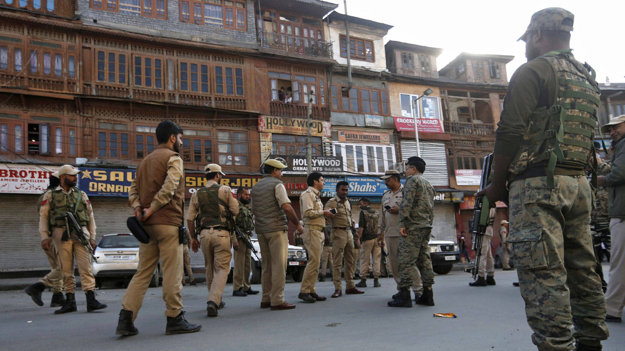 Indian 桌布 壁紙 — 身穿制服的警察和士兵在繁忙的街道上保持警覺，街道兩旁是木造建築和商店門面。