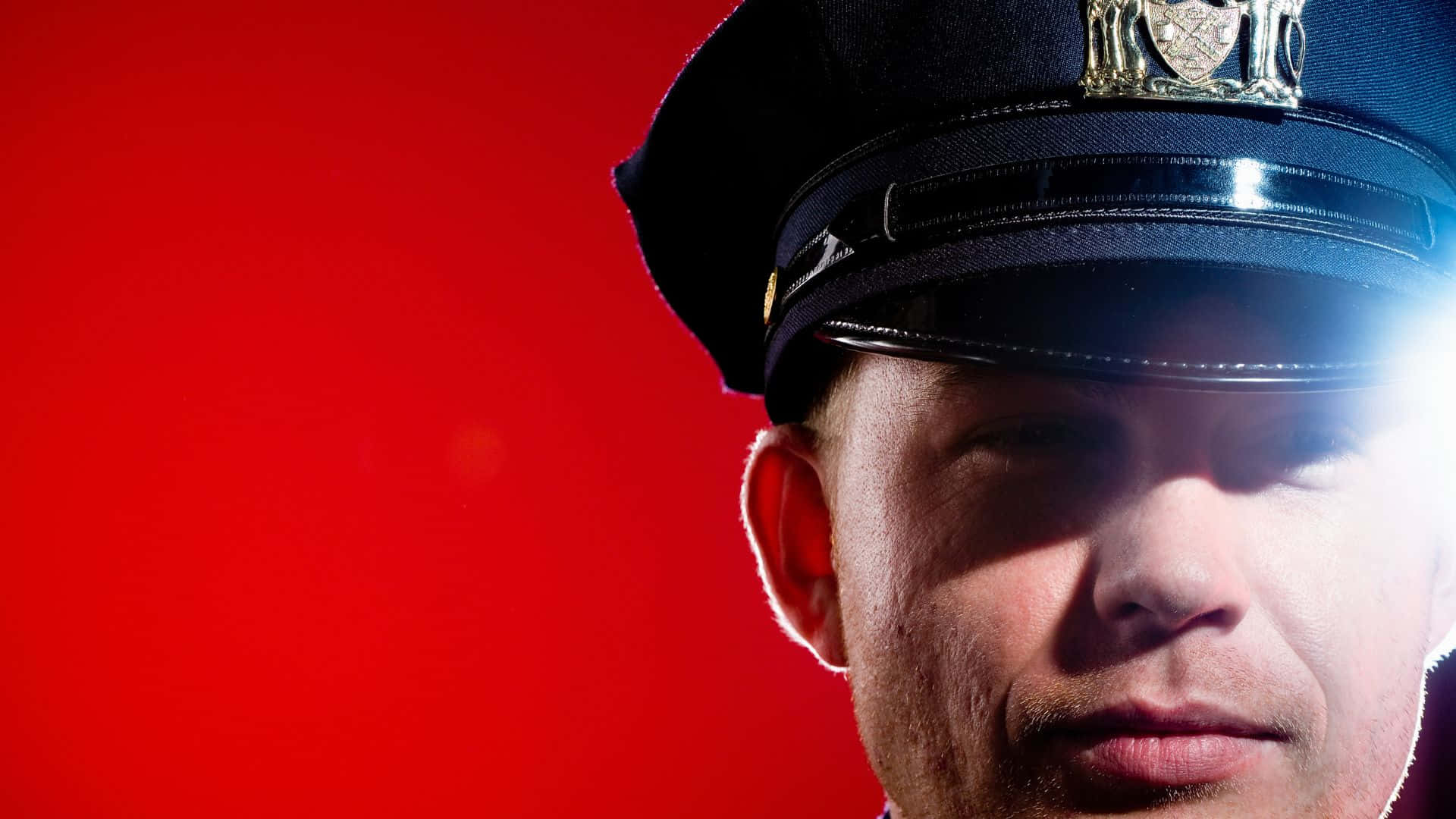 cop 桌布 壁紙 — 身穿制服的警察特寫肖像，背景為鮮紅色，光線戲劇性。