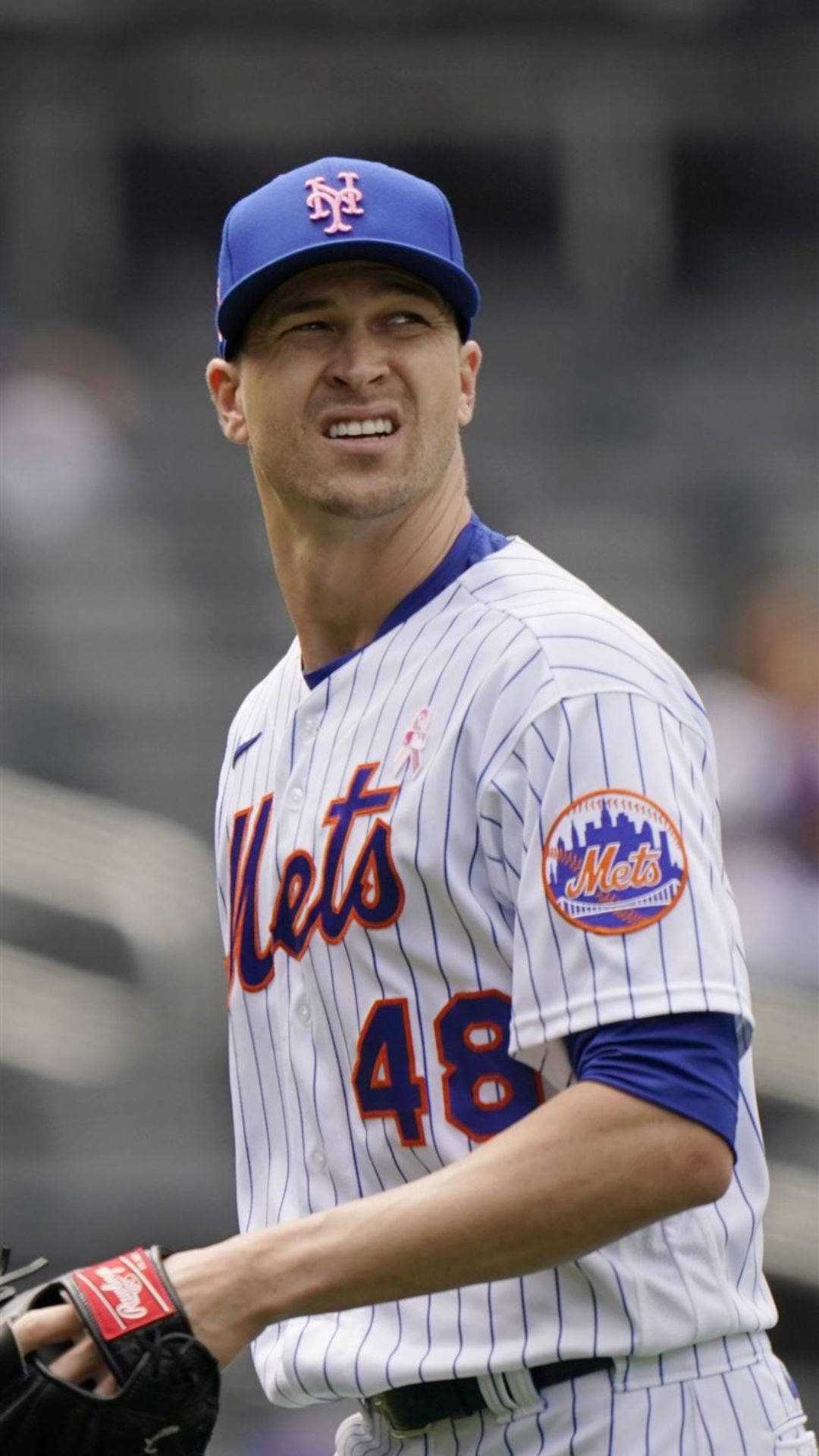 Degrom 桌布 壁紙 — 身穿大都會隊球衣的棒球選手在日間比賽中自信微笑，背景是模糊的球場座位。