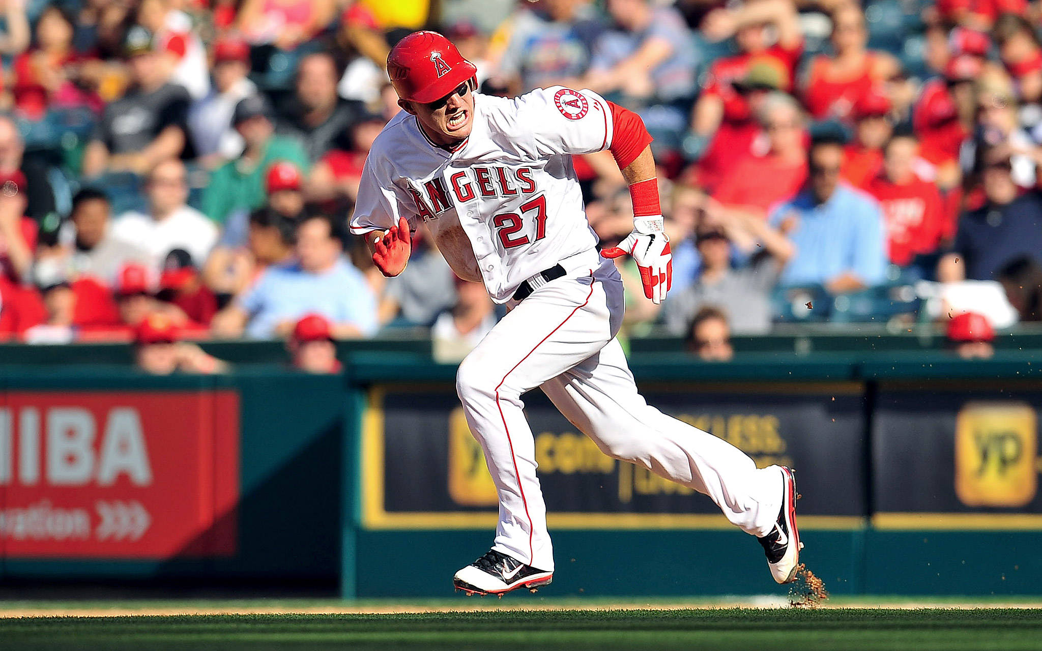 Mike Trout 桌布 壁紙 — 身穿天使隊球衣的棒球運動員在陽光明媚的球場上衝刺，背景是歡呼的觀眾。