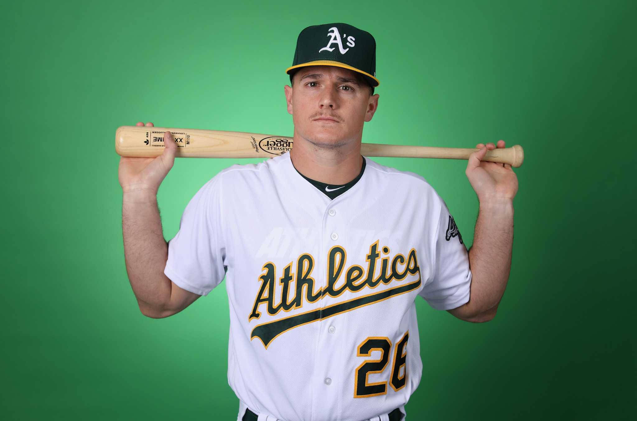 baseball bat 桌布 壁紙 — 身穿奧克蘭運動家隊球衣的棒球選手，在純綠色攝影棚背景前將球棒扛在肩上。