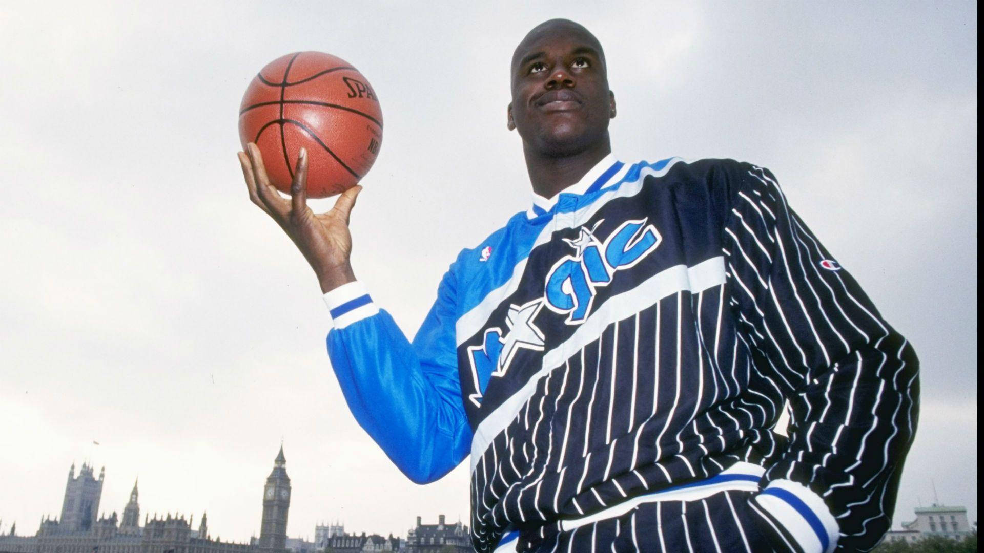 Shaquille O'neal 桌布 壁紙 — 身穿奧蘭多魔術隊球衣的高大籃球運動員，在倫敦天際線前手持籃球，背景是大笨鐘。