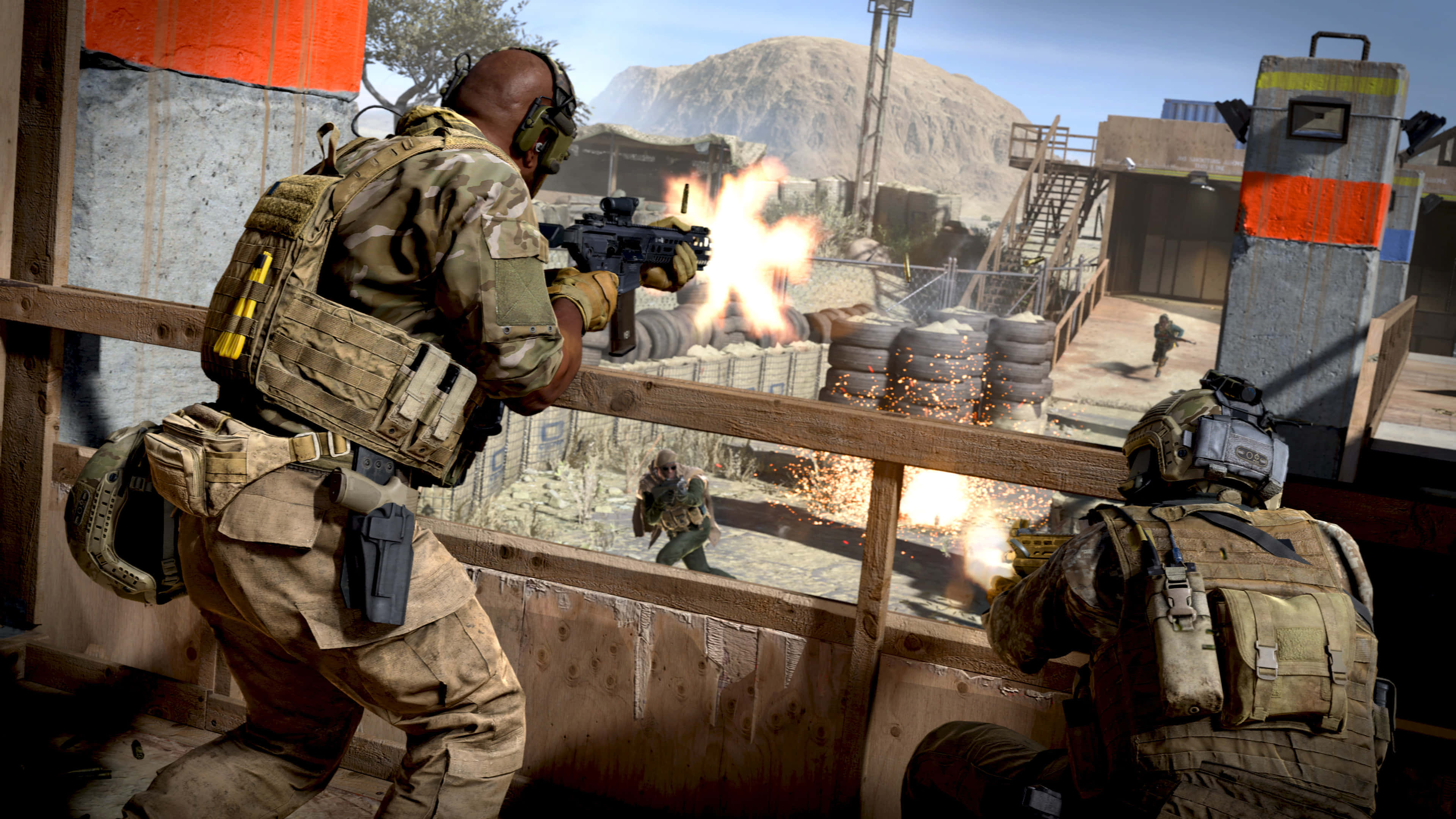 HD Call Of Duty Modern Warfare 桌布 壁紙 — 身穿戰術裝備的士兵在沙漠軍事基地中，從木製路障開火，同時爆炸四起。