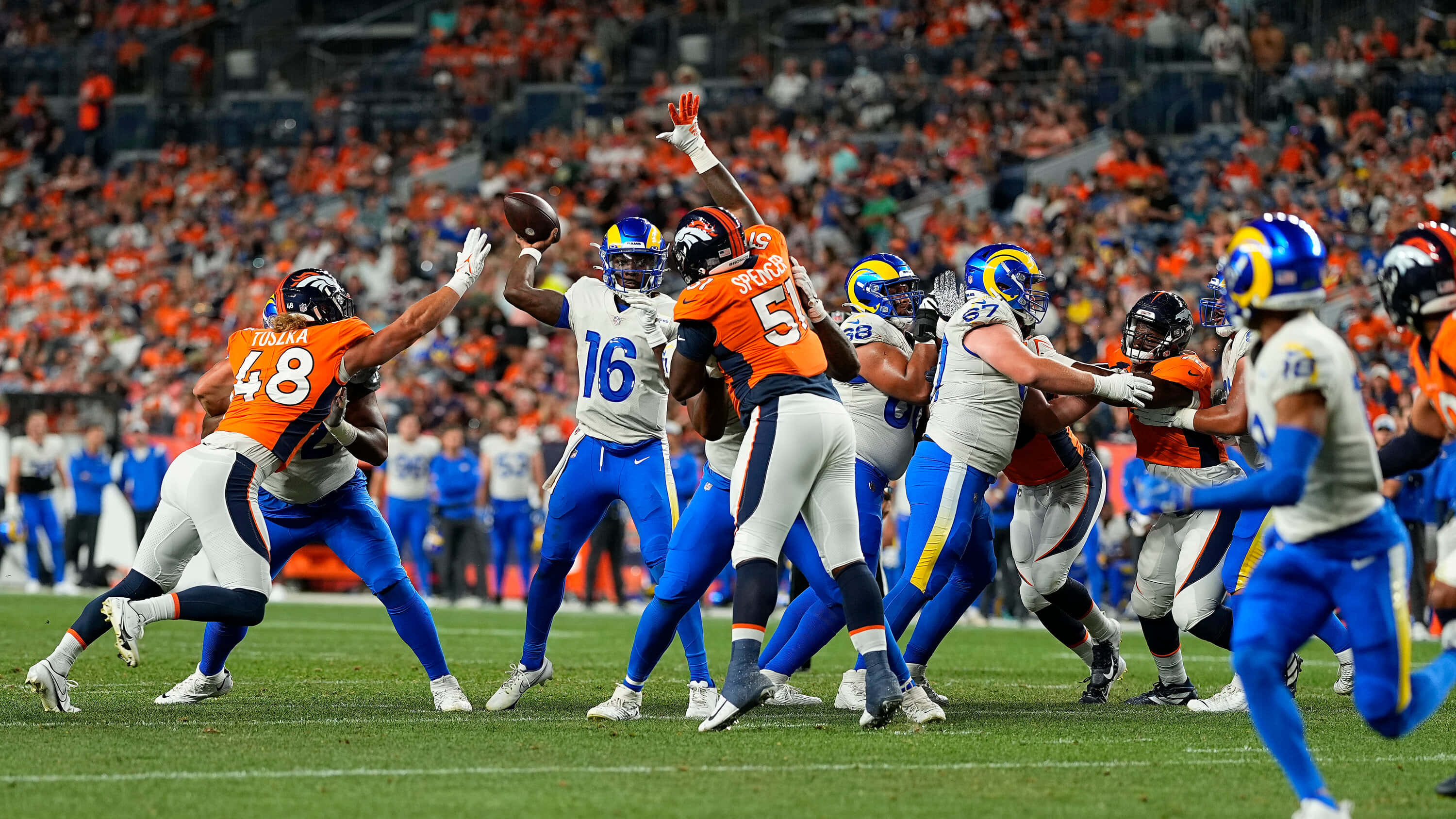 NFL 桌布 壁紙 — 身穿橙色和藍色制服的美式足球運動員在座無虛席的體育場比賽中激烈爭奪傳球。