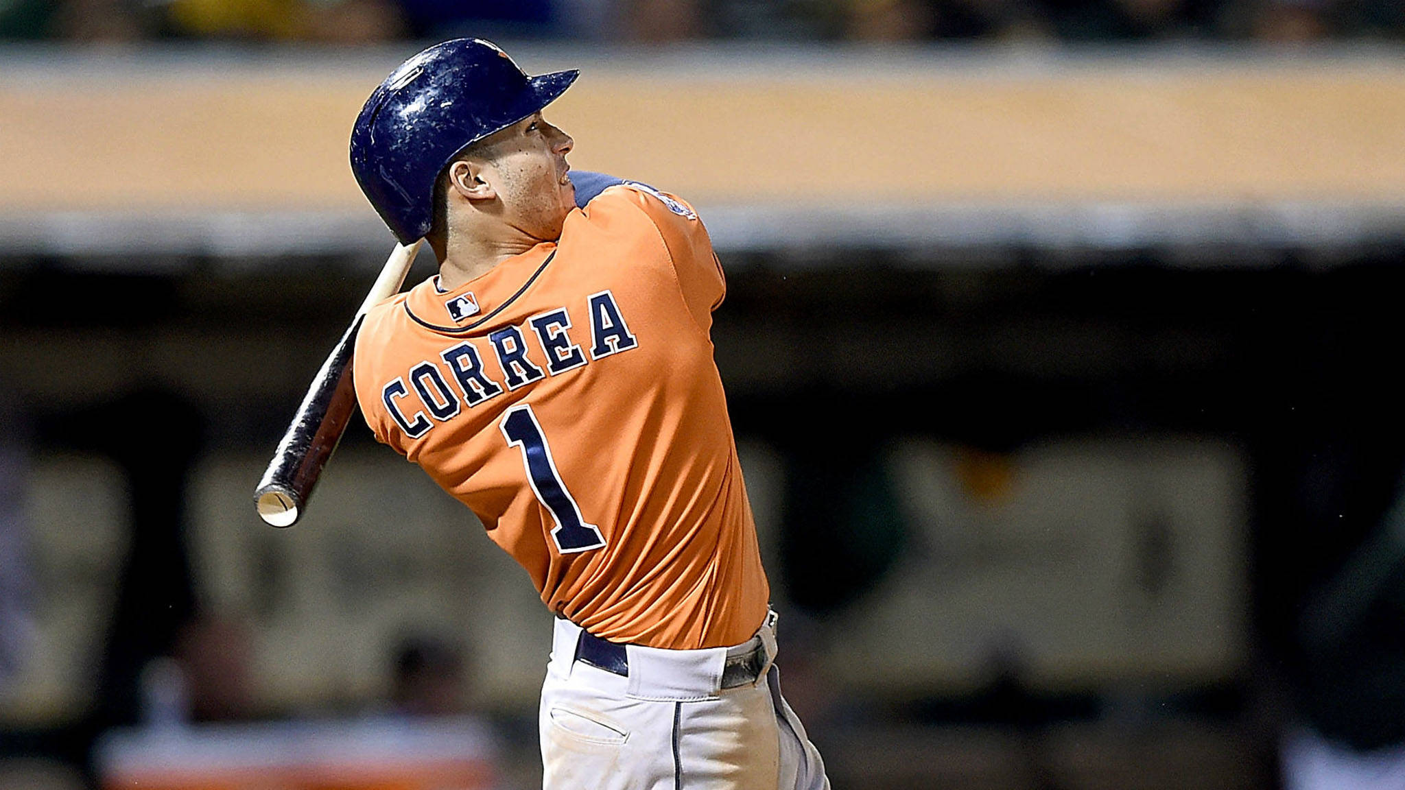 Carlos Correa 桌布 壁紙 — 身穿橙色球衣的棒球選手Correa在夜間比賽中專注地揮棒。
