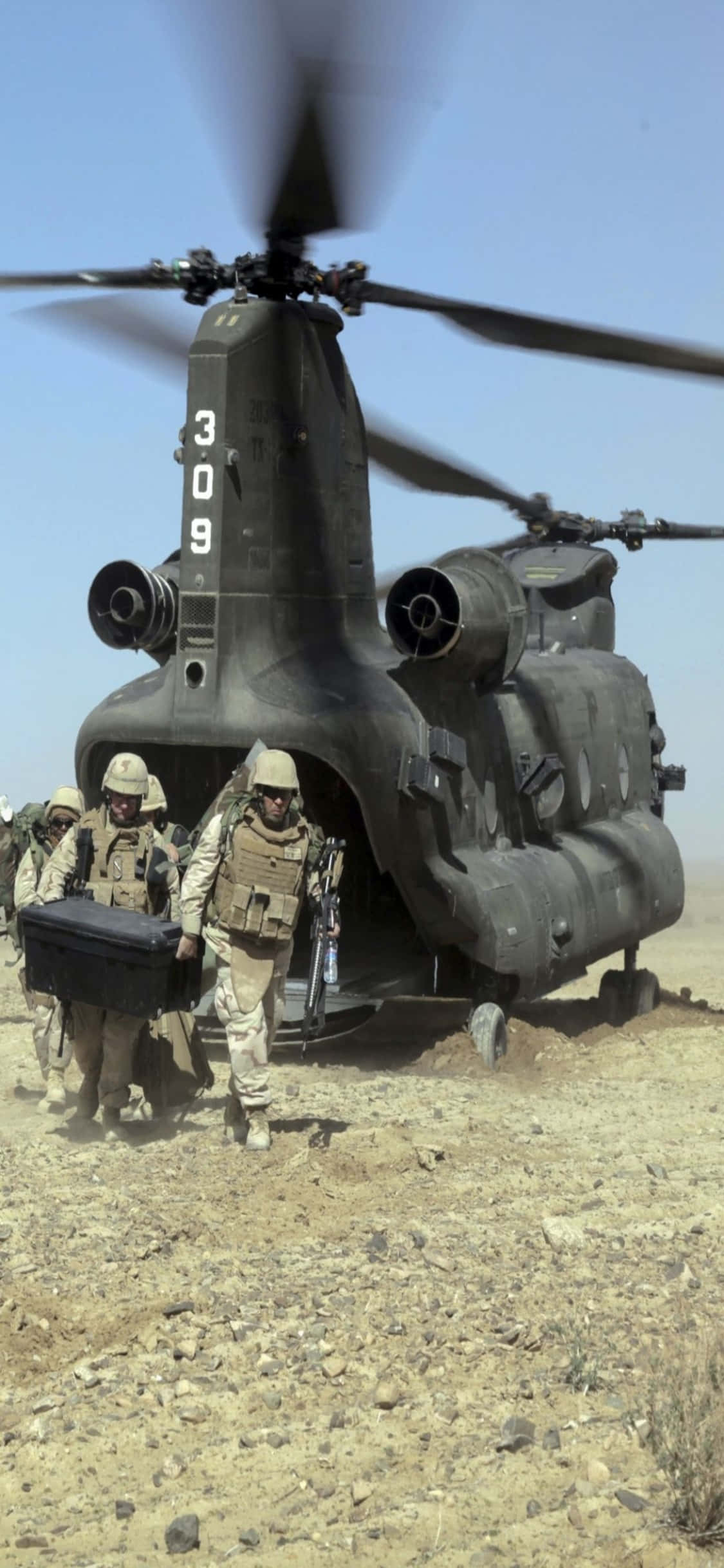 iPhone Xs Helicopters 桌布 壁紙 — 身穿沙漠裝備的士兵從一架標有309的大型軍用直升機中走出，背景是清澈的藍天。