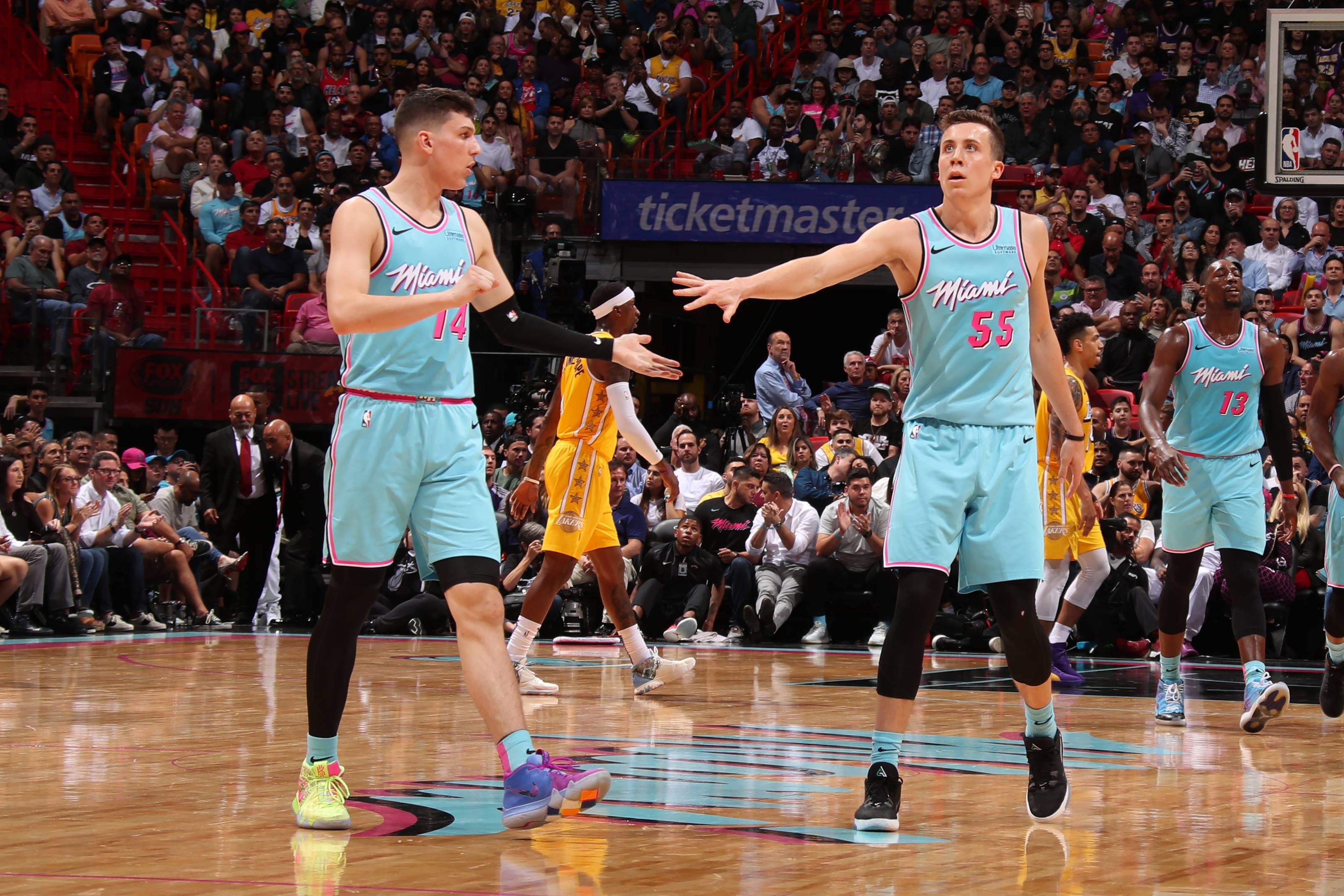 duncan robinson 桌布 壁紙 — 身穿淺藍色球衣的邁阿密熱火球員在籃球比賽中做出手勢，背景是座無虛席的觀眾。