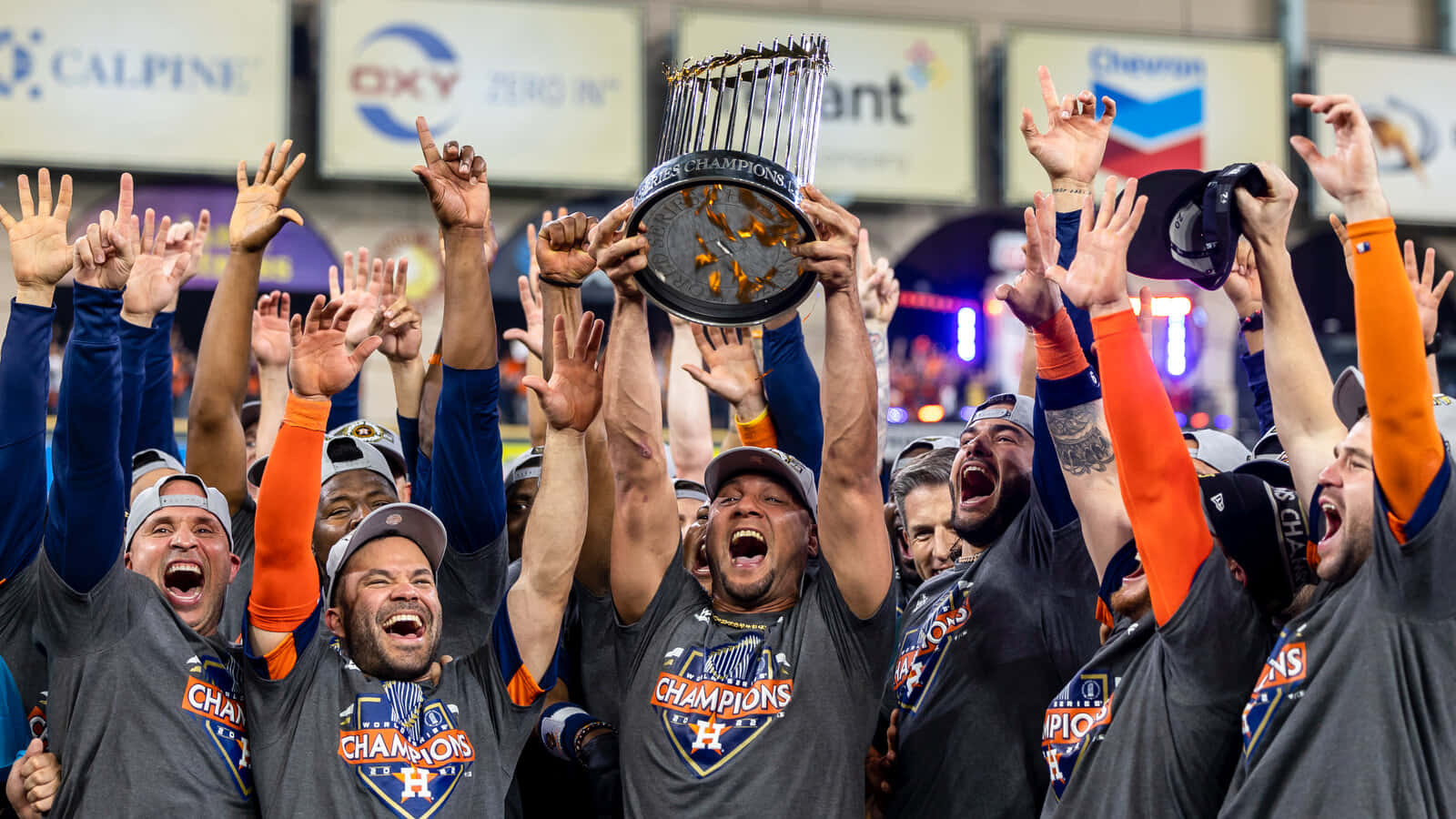 Astros 桌布 壁紙 — 身穿灰色「Champions」球衣的棒球運動員歡呼雀躍，高舉閃閃發光的獎盃，雙臂高舉慶祝勝利。
