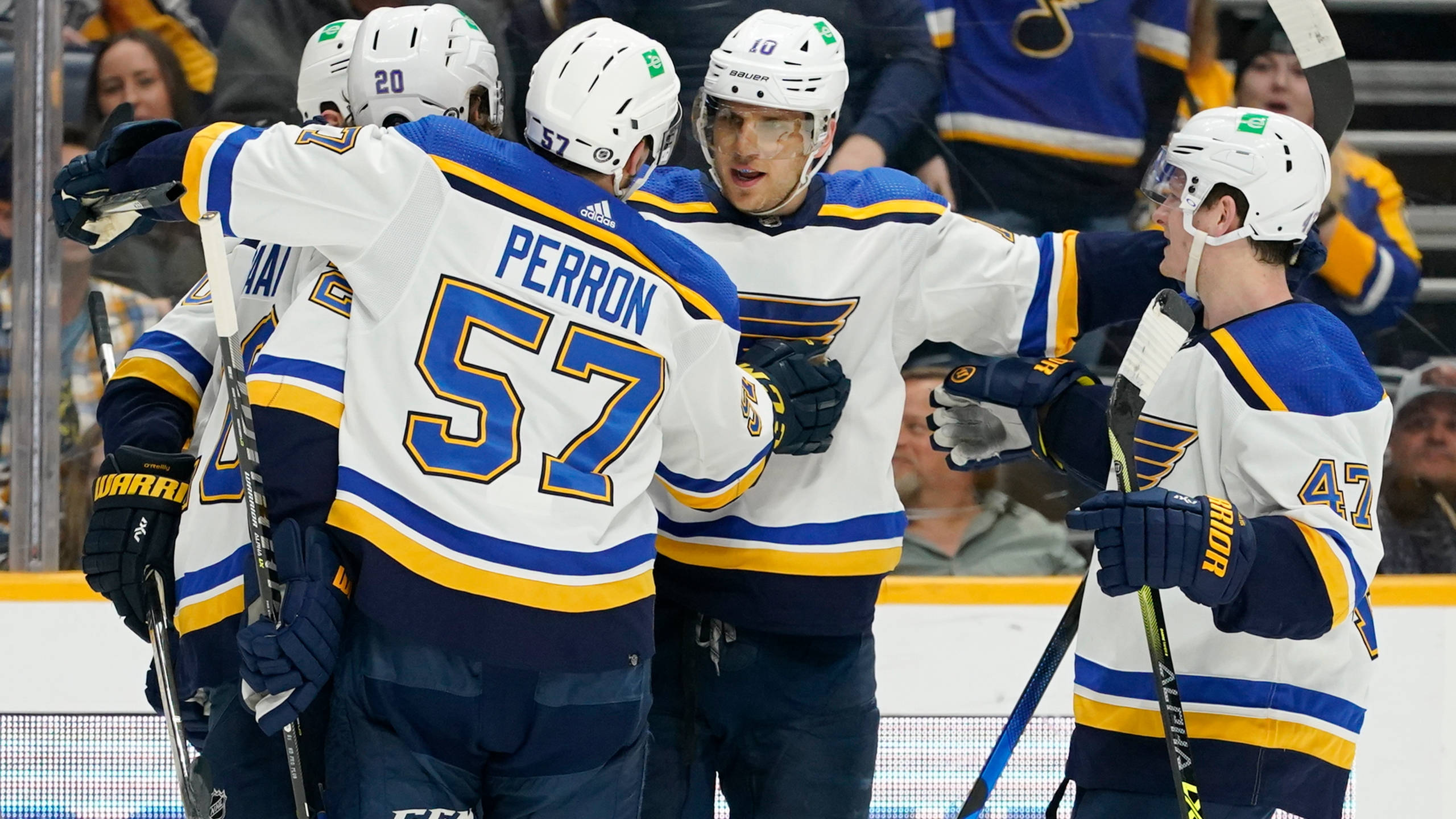 Nashville Predators 桌布 壁紙 — 身穿白色、藍色和金色球衣的冰上曲棍球運動員戴著頭盔和球棍在冰上慶祝進球。