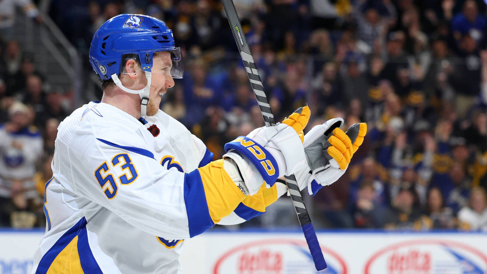 hockey 桌布 壁紙 — 身穿白色、藍色和黃色球衣的冰球運動員在場館人群中高舉球棍慶祝。