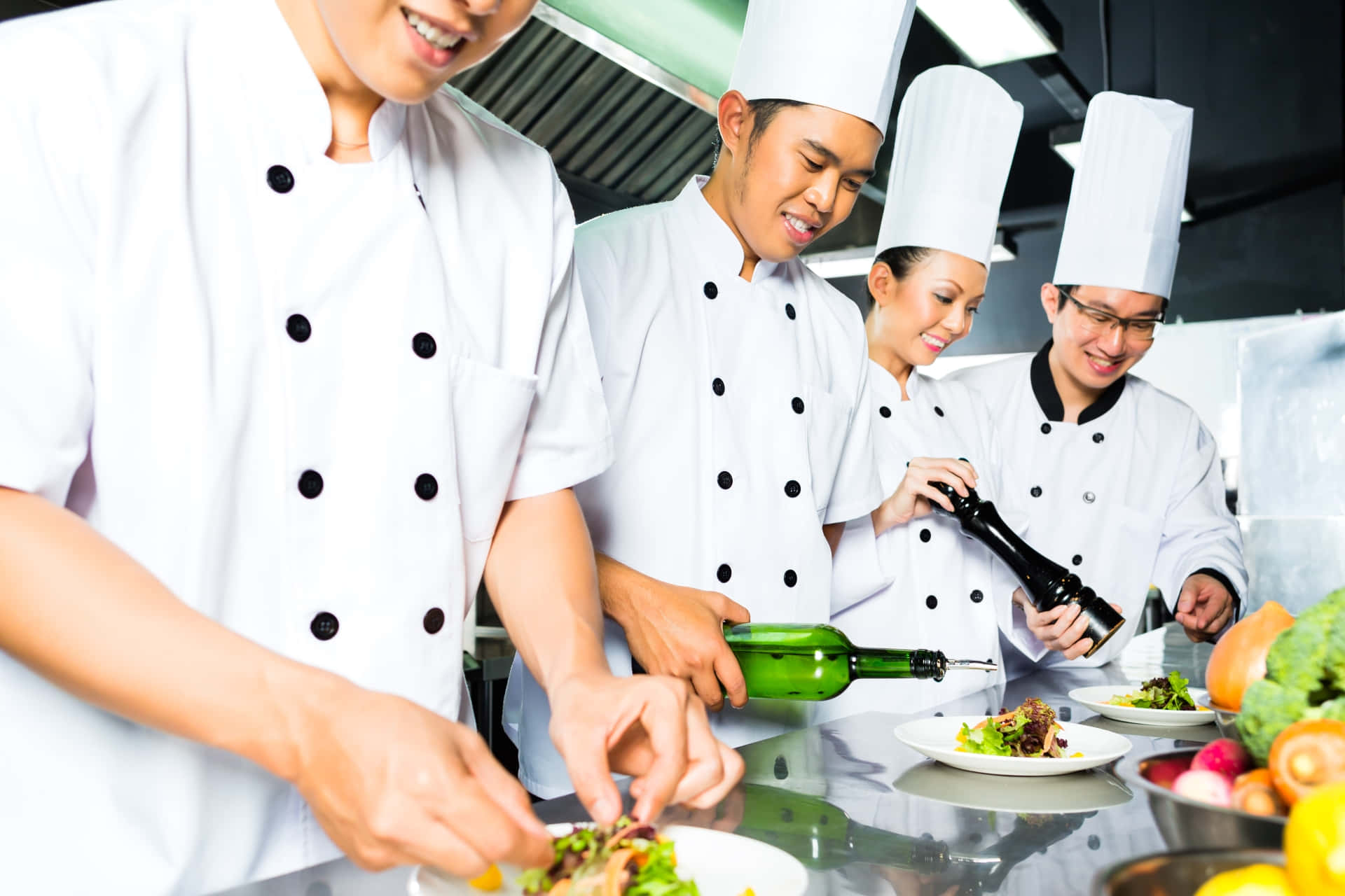 Hospitality 桌布 壁紙 — 身穿白色制服的廚師在明亮的專業廚房裡，用新鮮蔬菜和橄欖油準備色彩繽紛的沙拉。