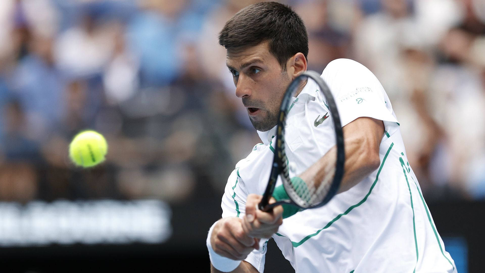 Australian Open 桌布 壁紙 — 身穿白色和綠色球衣的網球選手在比賽中專注地揮拍擊打亮黃色的球。