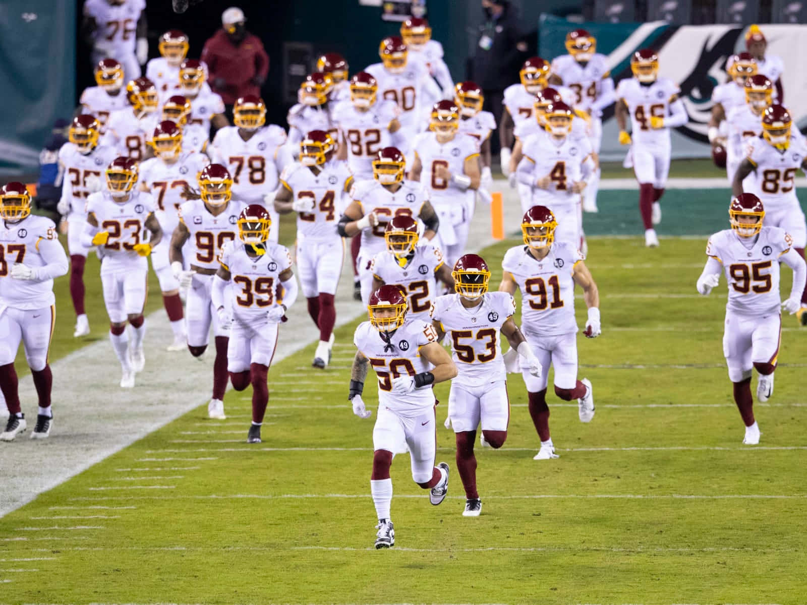 足球隊身穿白色和酒紅色球衣跑入球場。 — NFL GIF 壁紙