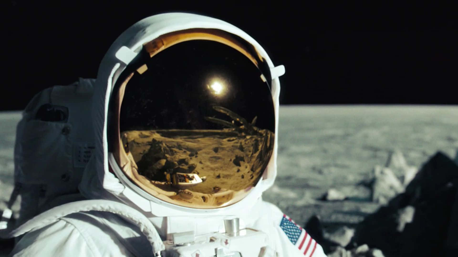 Astronaut Desktop 桌布 壁紙 — 身穿白色太空衣的太空人凝視著頭盔面罩反射的地球，背景是黑色天空下的月球表面。
