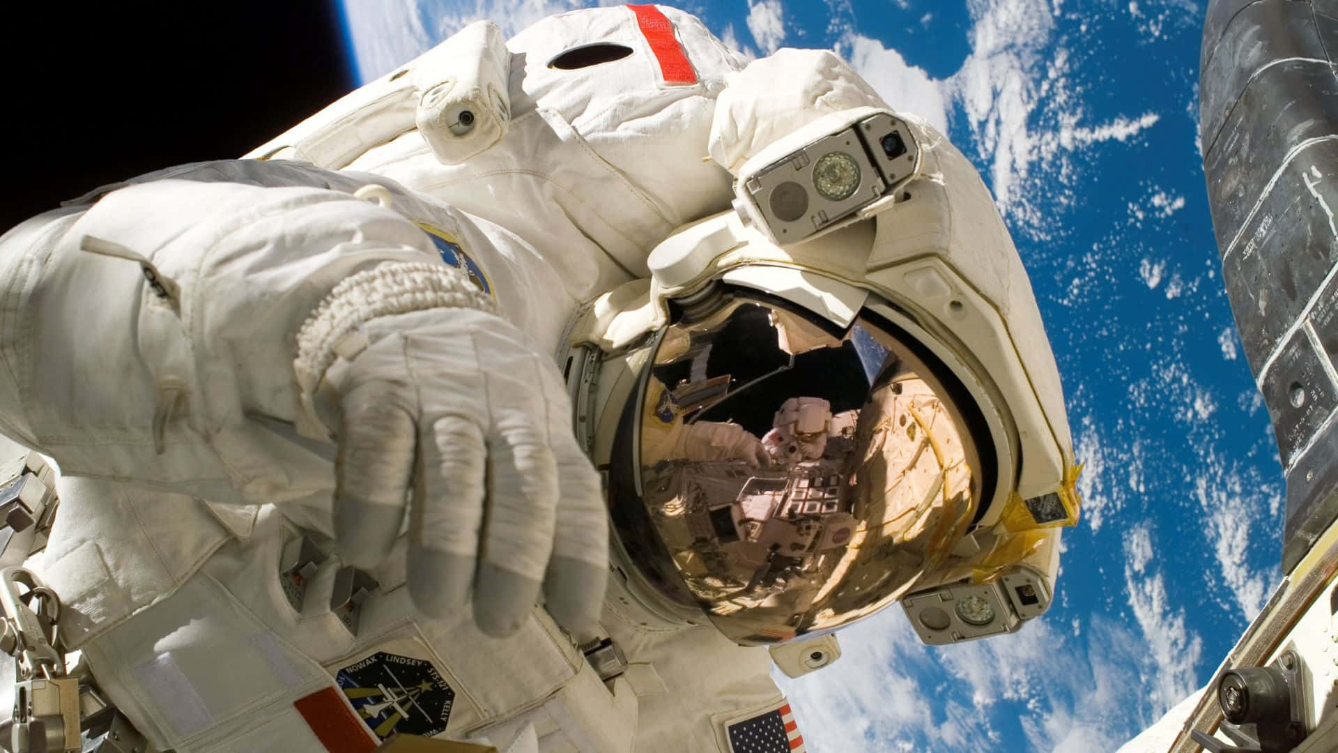 Live Space 桌布 壁紙 — 身穿白色太空衣的太空人在太空船外漂浮，背後可見地球的藍白雲層。